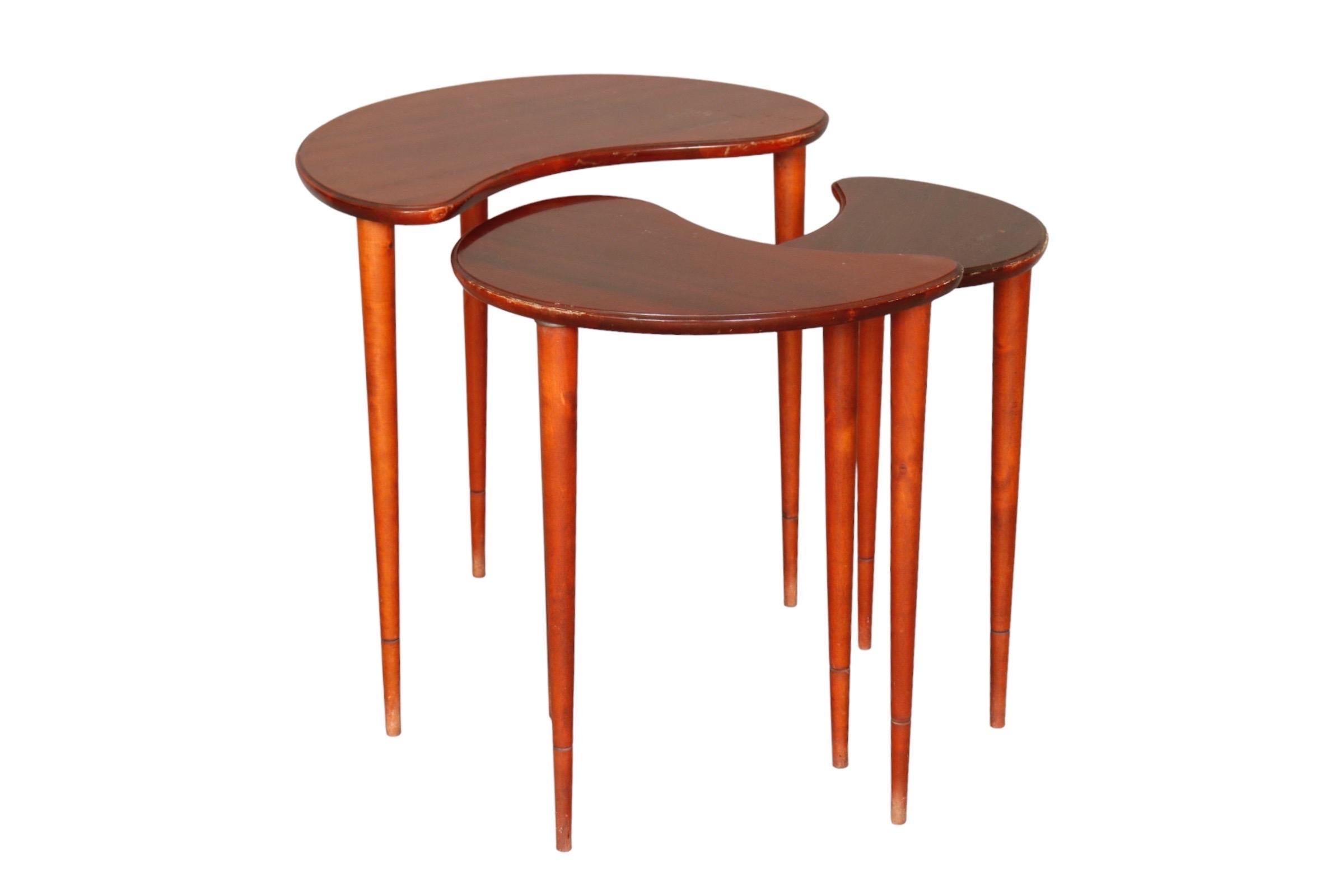 A set of three kidney shaped nesting tables. Beveled table tops are supported on sleek round tapered legs.

Measures: L:21.25”
W:15”
H:20.5”