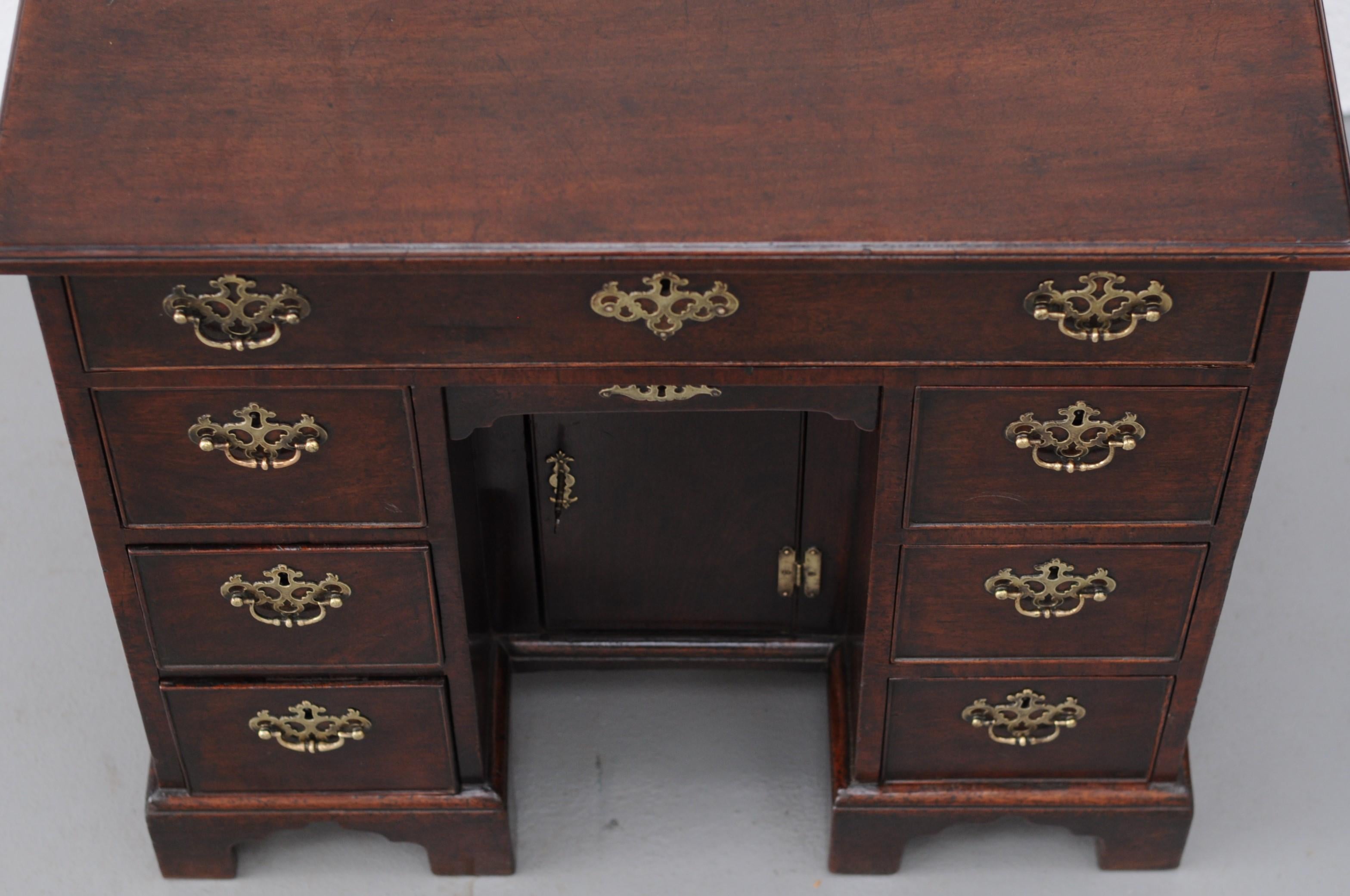 A good quality George III period mahogany kneehole desk with moulded edge top above a long drawer and arrangement of three graduated small drawers either side of a recessed kneehole cupboard and small apron drawer above. standing on shaped
bracket