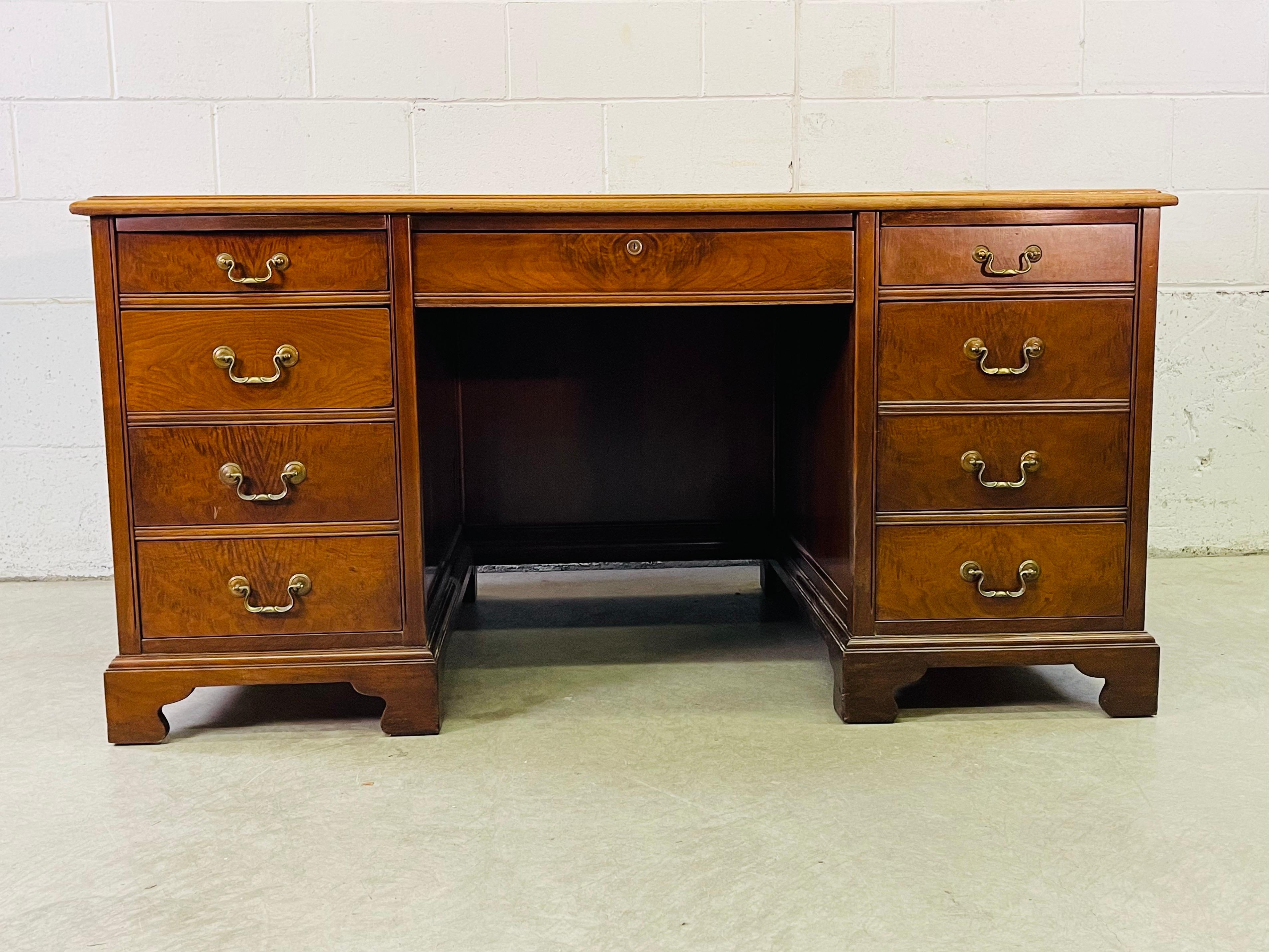 Vintage 1980s mahogany wood executive style desk. The desk has 8 drawers and two flat pull out side drawers. The back of the desk is finished. There is a opening on the top for wires to pass through. Chair clearance is 25” L x 24.5” H. Marked Jasper