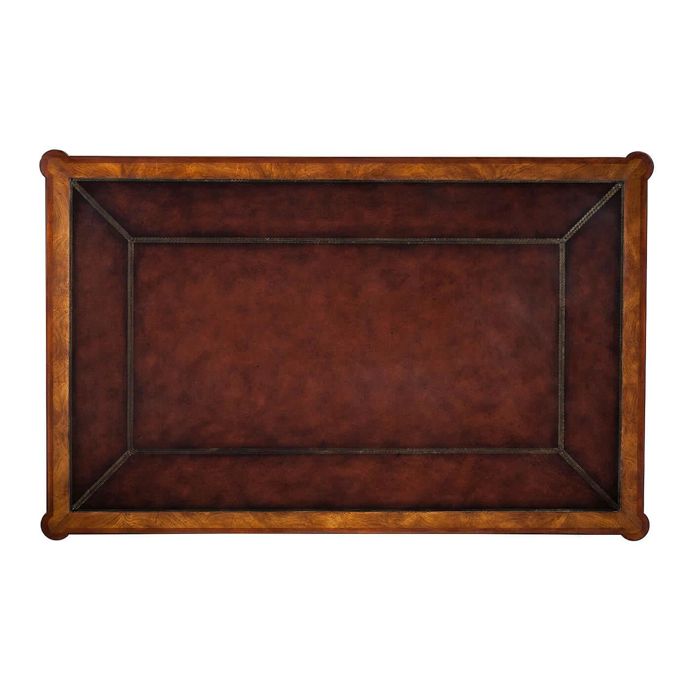 A mahogany and flame veneered writing table, the tooled leather inset top with protruding rounded corners above three frieze drawers on turned legs with brass castors.

Dimensions: 55.5