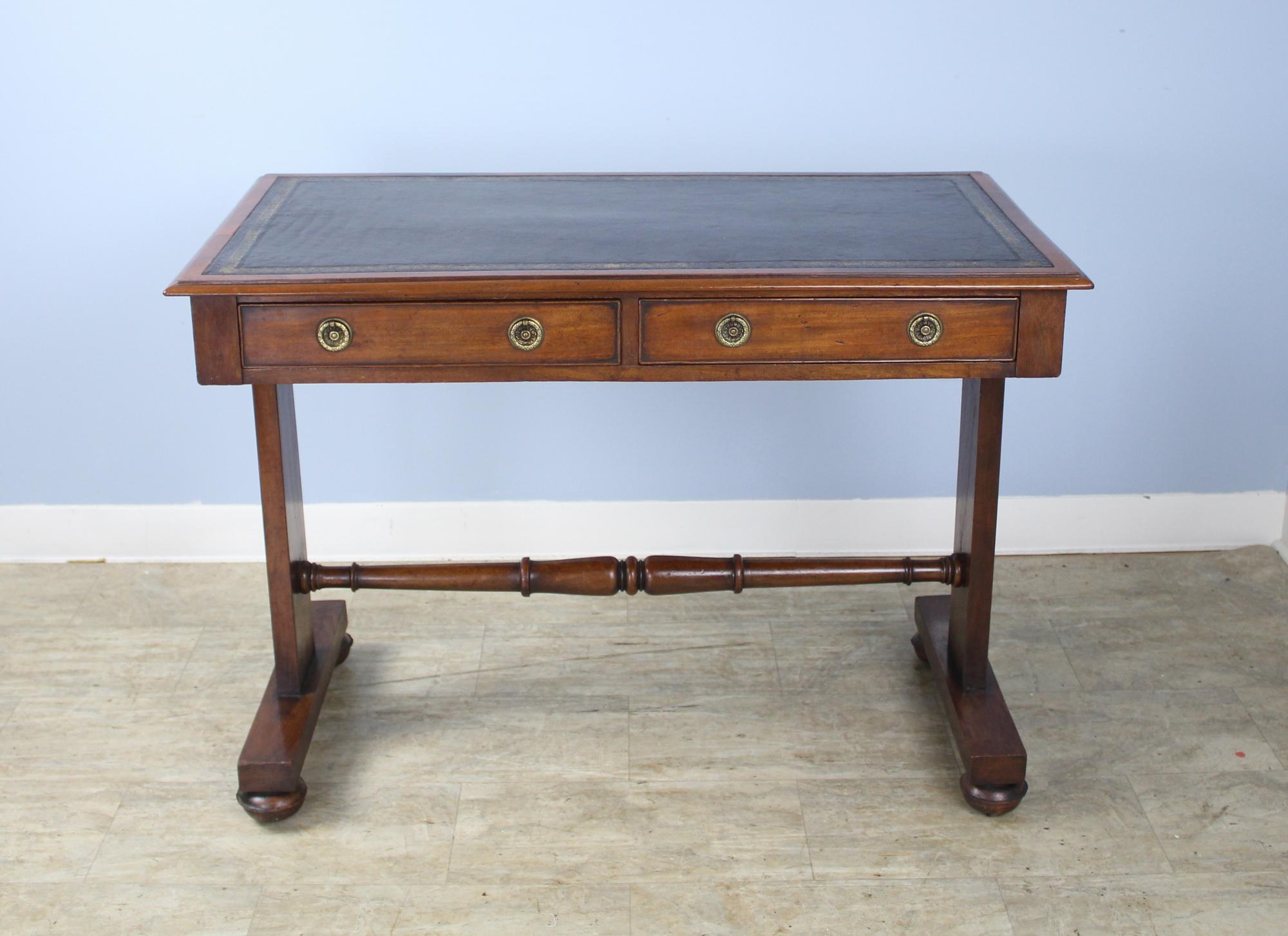A handsome mahogany writing table or desk with new dark brown leather top. The whole piece has been lightly refinished. Two roomy drawers on one side and turned trestle base is quite handsome. Apron height is a very comfortable 25 inches.