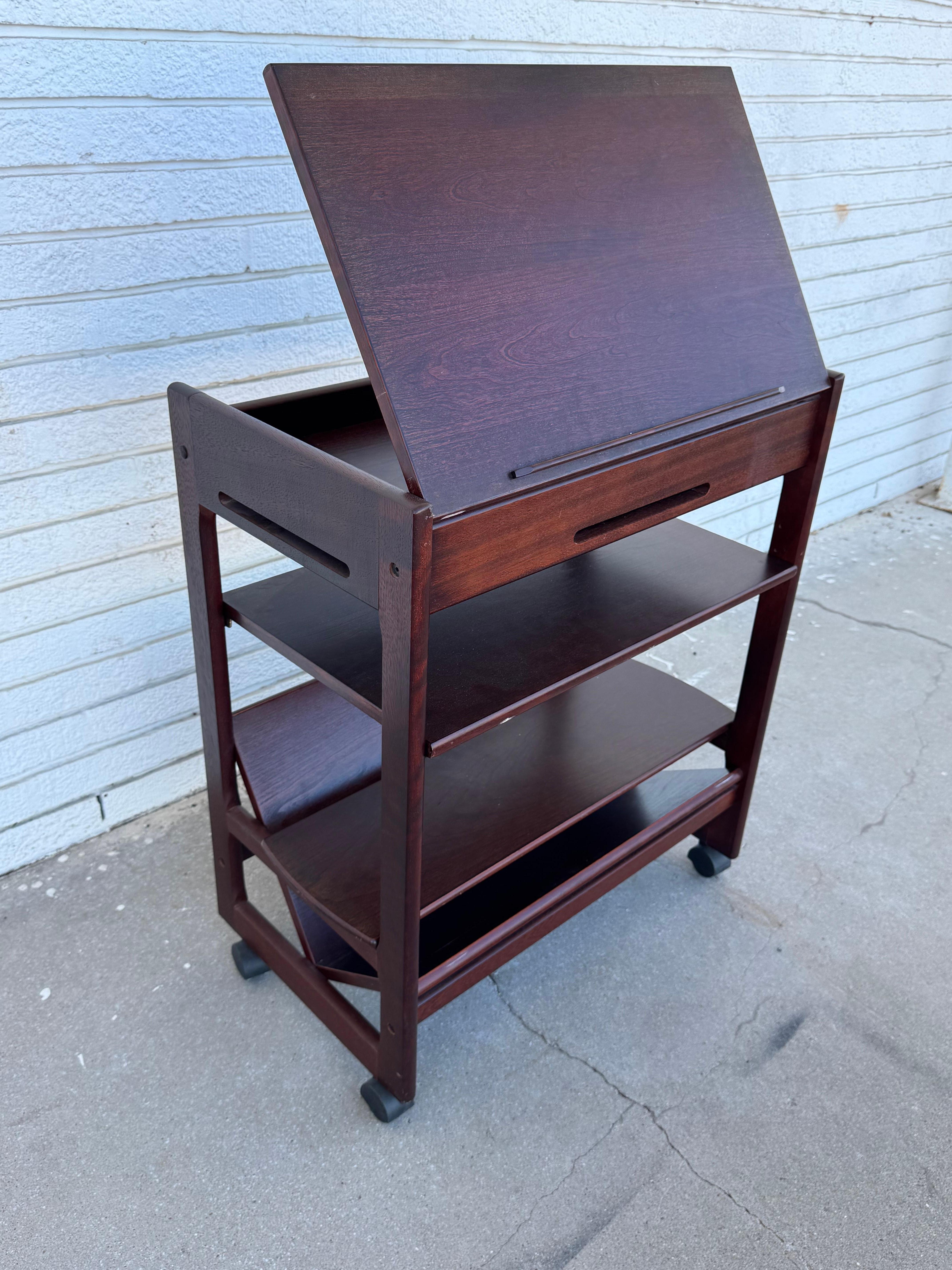 This levenger table has multiple shelves and comes with casters for easy mobility. The top raises to expose a storage area that great for storing cookbooks and the like. 
