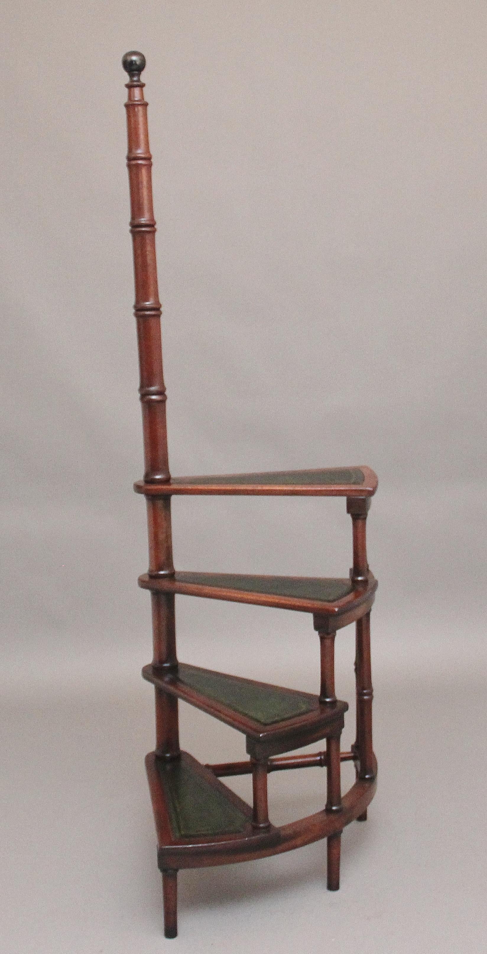 A set of mid 20th Century mahogany library steps, consisting of four steps with each step lined with a green leather decorated with blind and gilt tooling, supported on a tall turn column with an ebonised turned knob at the top, with various turned