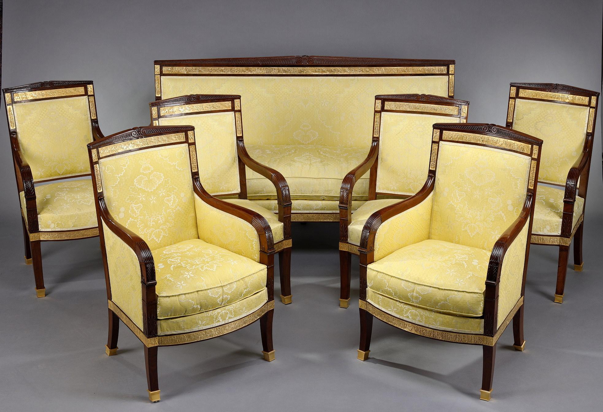 Early 19th-century salon with a suite of four armchairs, two bergères and a sofa in carved mahogany, decorated with gilded bronze mounts and chased in relief with scenes from Roman history. Pedimented backs and saber feet.