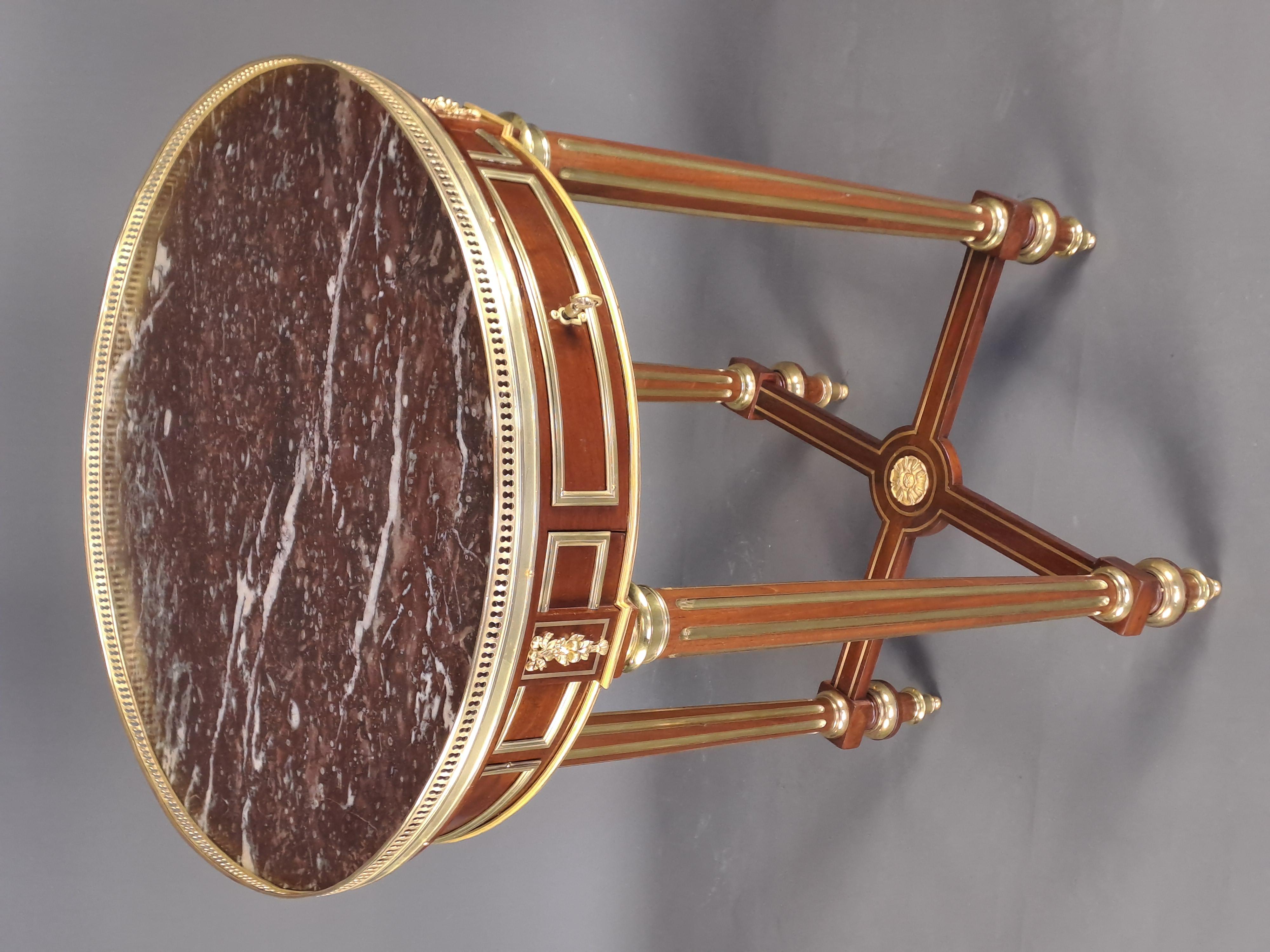 Elegant Louis XVI gueridon topped with a royal Belgian marble surrounded by an openwork gallery in gilded brass, the belt is decorated with gilded bronze frames supported by floral motifs in gilded bronze above the four tapered and fluted brass