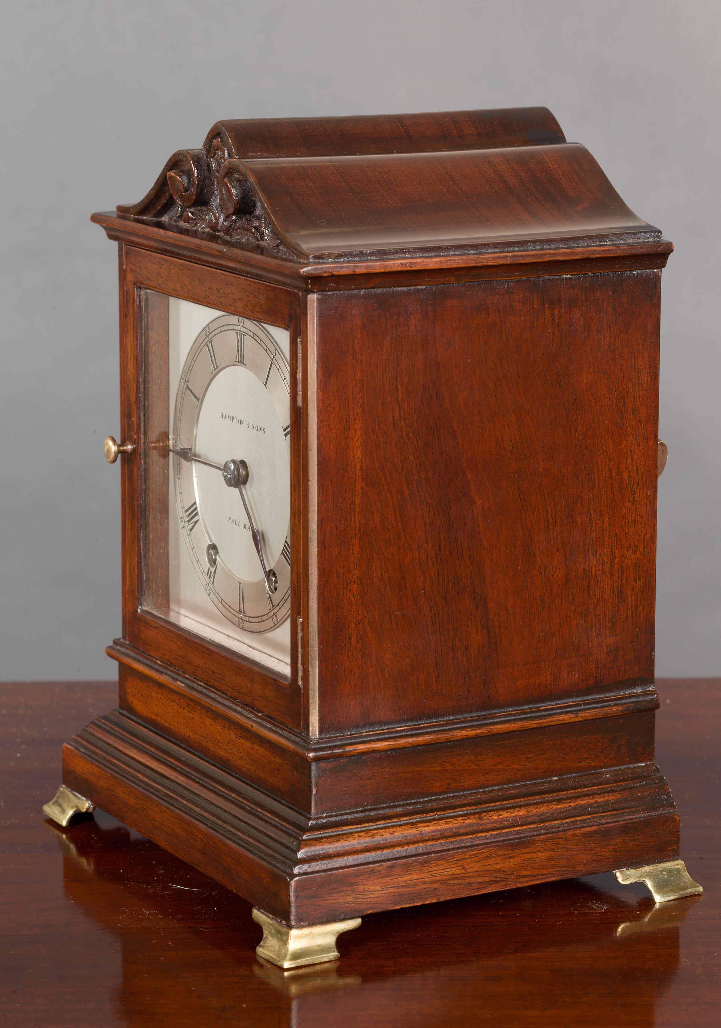 Mahogany cased mantel clock in a serpentine top case with carved decoration, standing on a stepped plinth and resting on brass bracket feet.

Glazed door opening to the silvered dial with raised chapter ring, Roman numerals and original ‘blued’