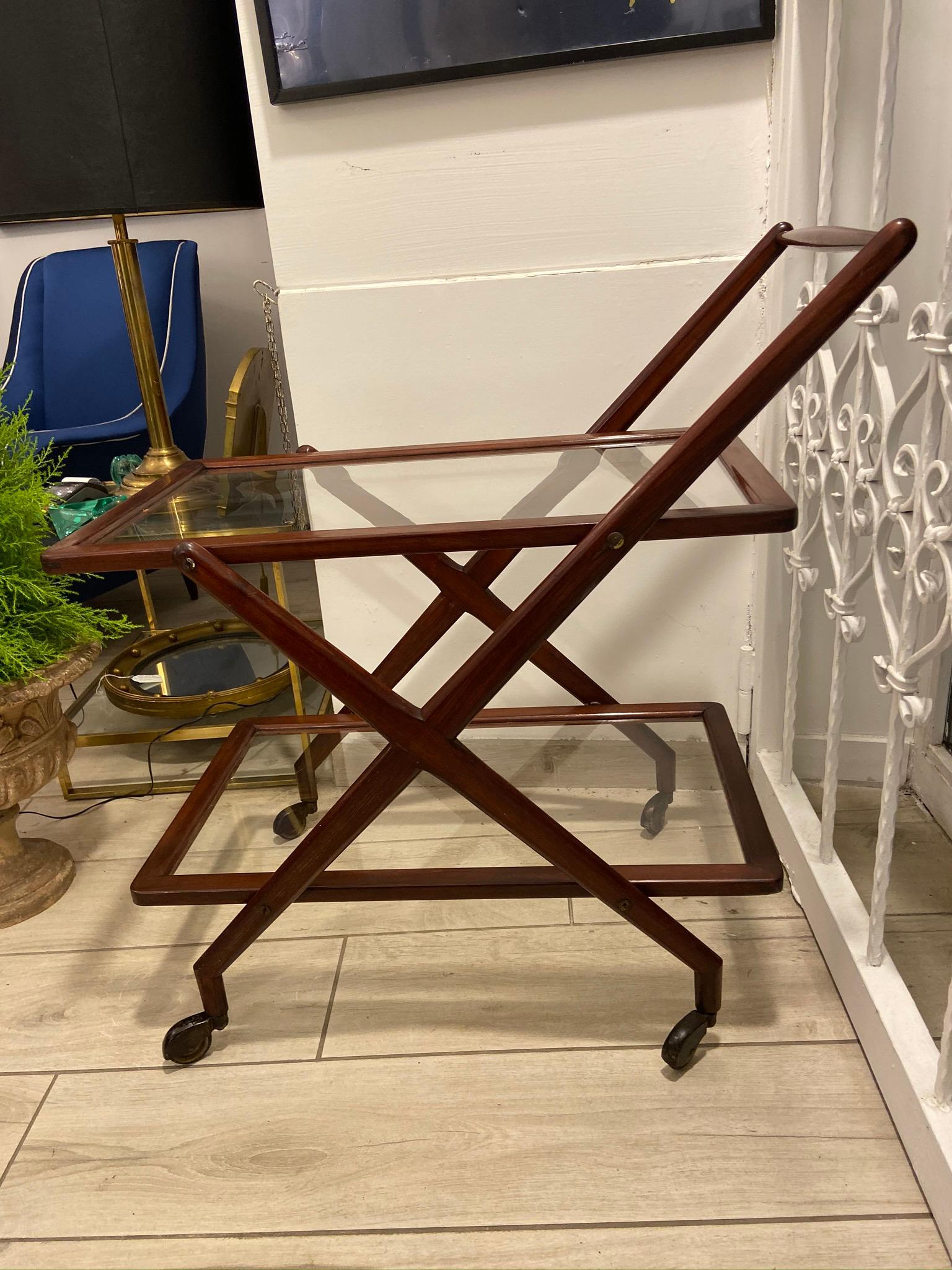 Mahogany Mid-Century Modern bar cart, in the manner of Italian designer Ico Parisi, 1960s. The sculptural bar cart features two glass shelves.