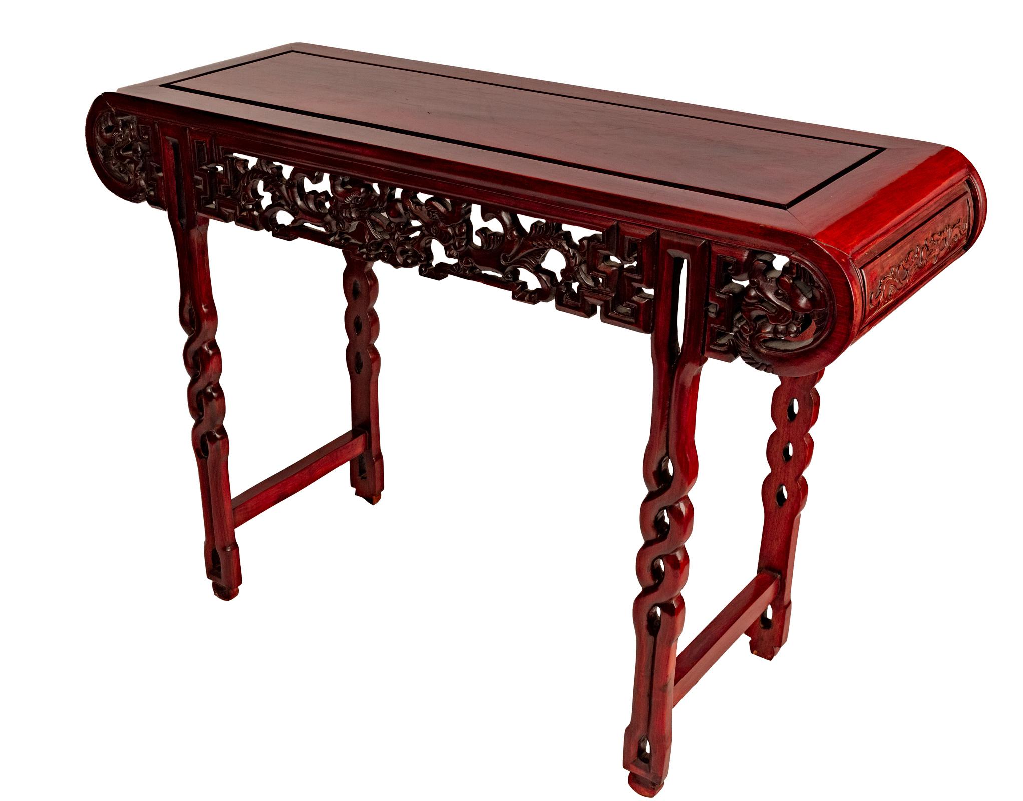 A mahogany Ming Chinese altar table with sides carved with scrolls and dragons, and legs in the form of intertwining branches, (circa 1915).