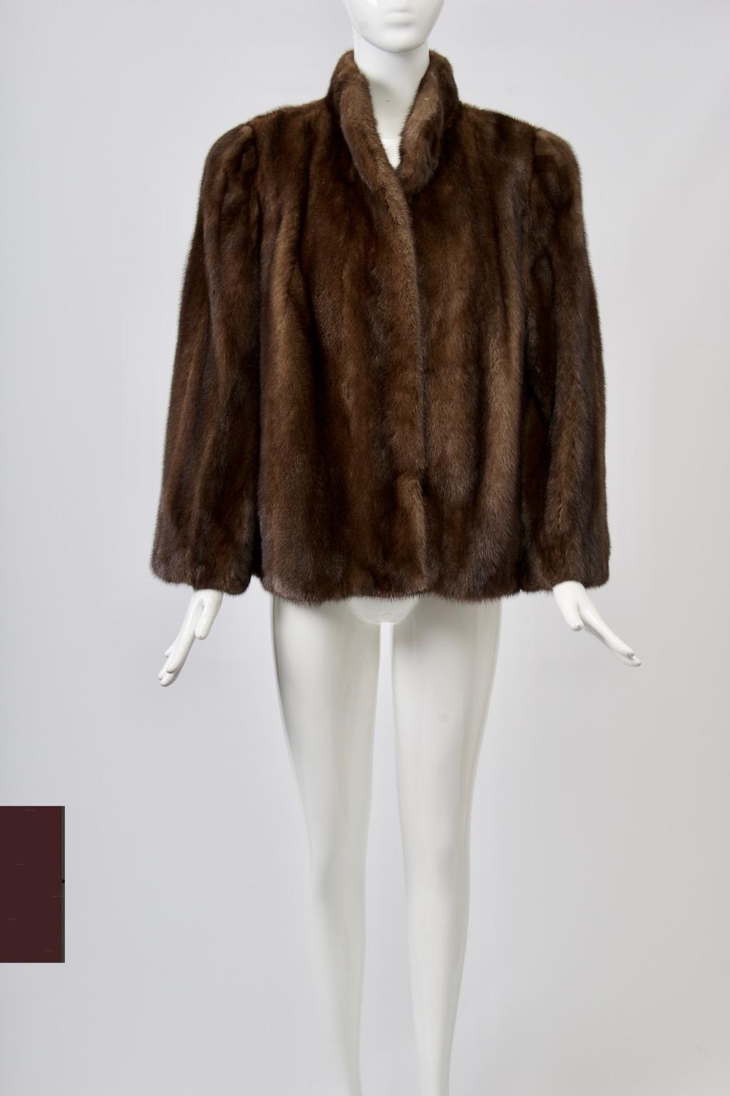 Vintage mahogany mink jacket with simple, straight cut features a stand-up collar, hidden slash pockets, and fur hook closures. Wrist-length sleeves are cut straight from shoulders with moderate shoulder pads. Complementary brown lining with