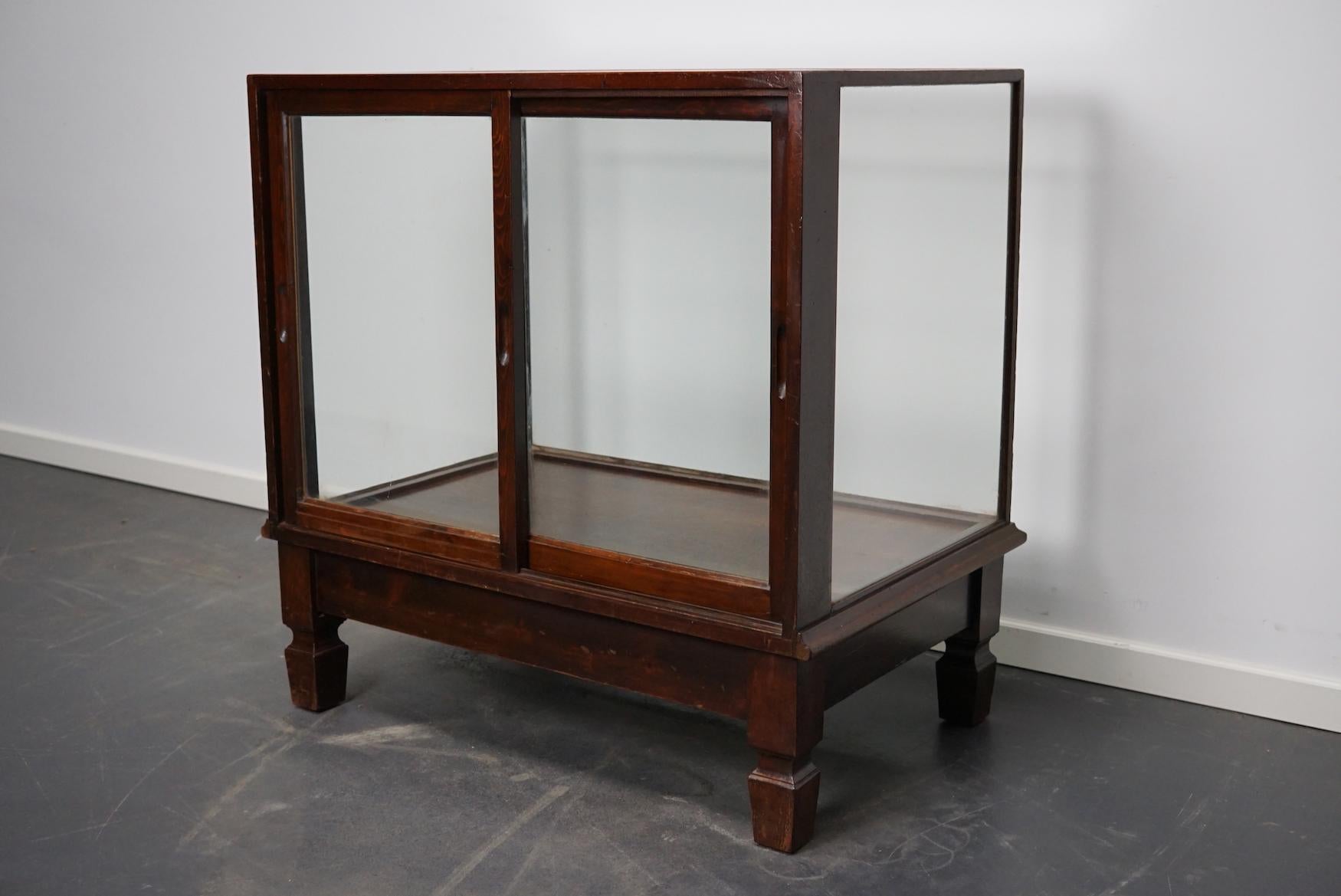 This mahogany and pine vitrine was made circa 1920s in England and probably used in a shop. It features a solid wooden frame with glass sides, top and sliding doors.