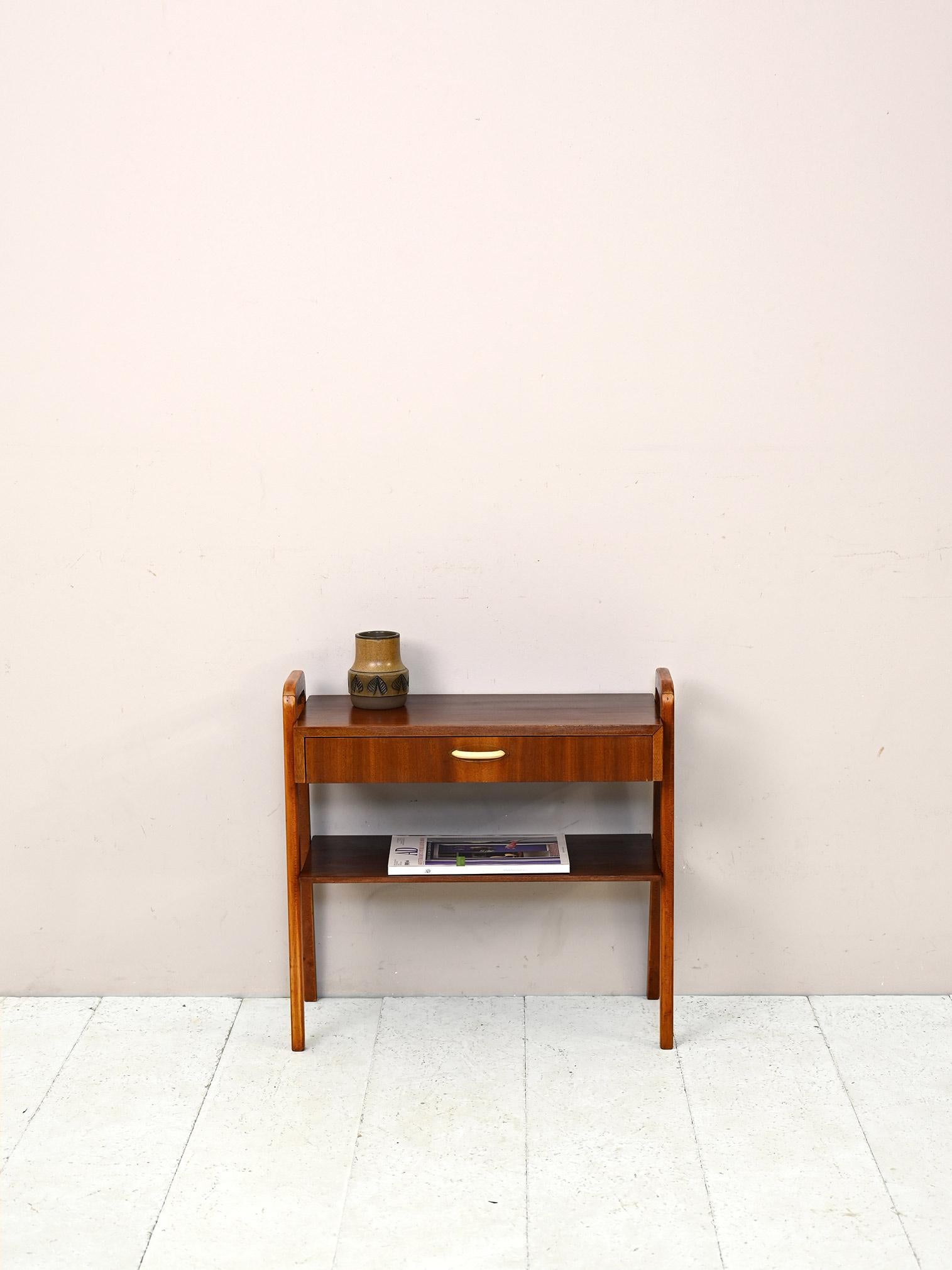 Vintage 1950s nightstand.

This piece of Scandinavian modernism features a convenient drawer with a white plastic handle and a magazine rack top. Square legs in the shape of an upturned U go to form two handles on the sides that allow the piece of