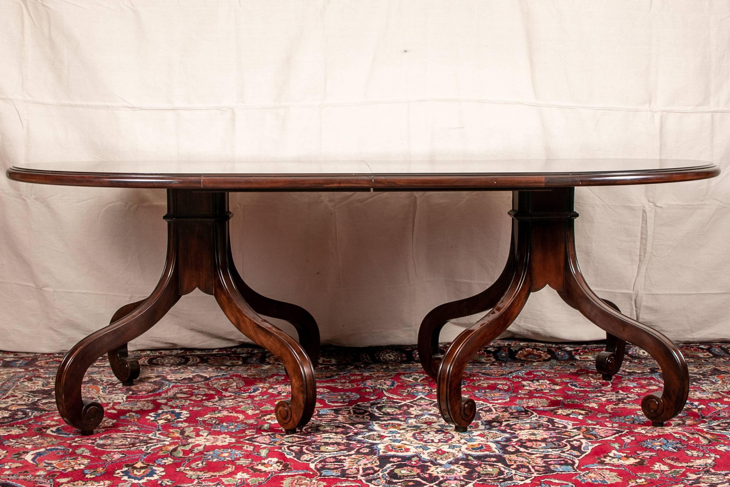 Oval dining table, mahogany, the two supports with four incurved scrolled legs each. Along with two leaves. Measures: W 18