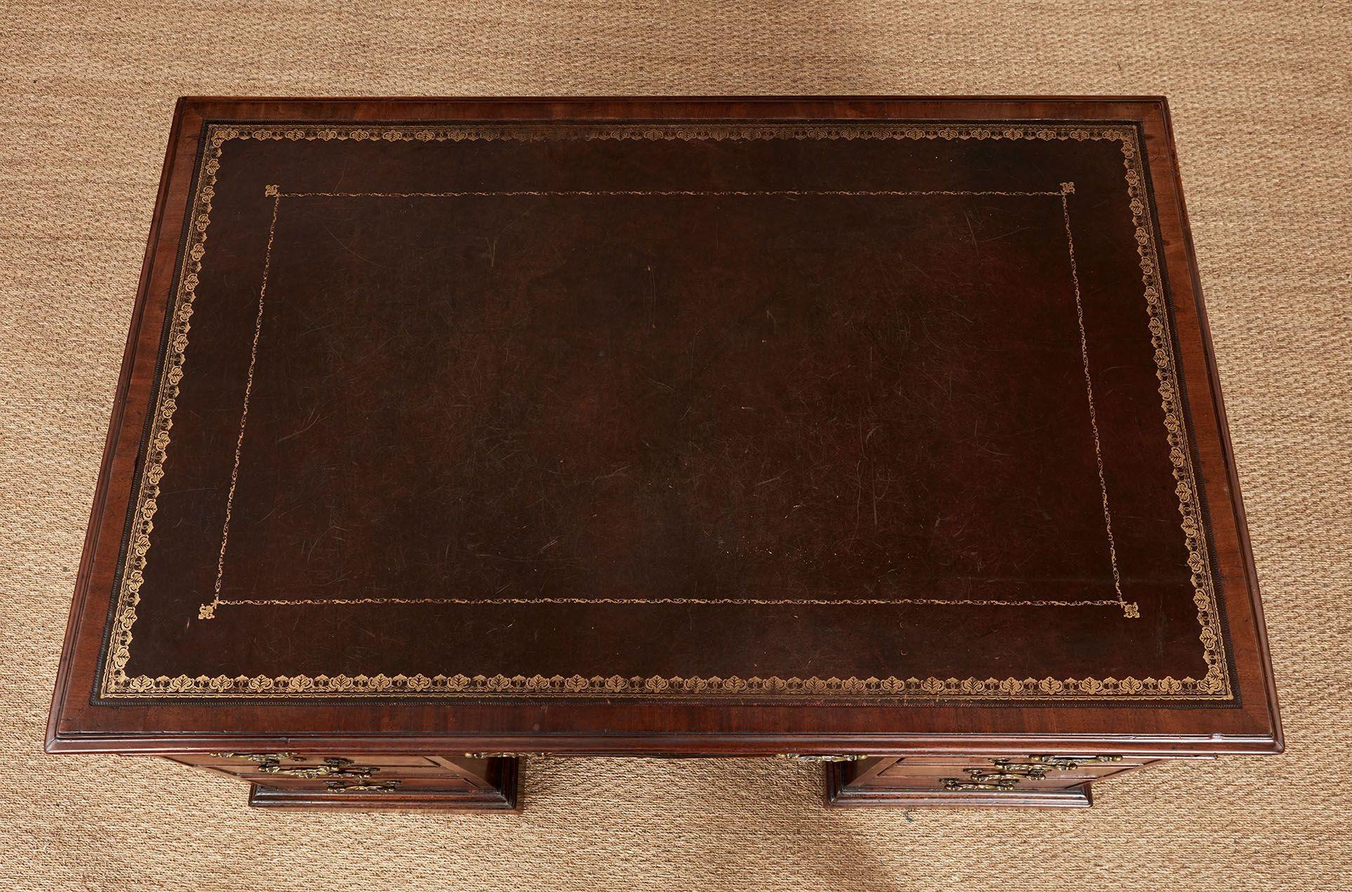 Scrivania inglese del XIX secolo in mogano ben figurato con piano a zoccolo e bordi modanati, con piano di scrittura in pelle con bordo dorato su due cassetti, su piedistalli con tre cassetti per lato su basi a zoccolo modellate con rotelle in