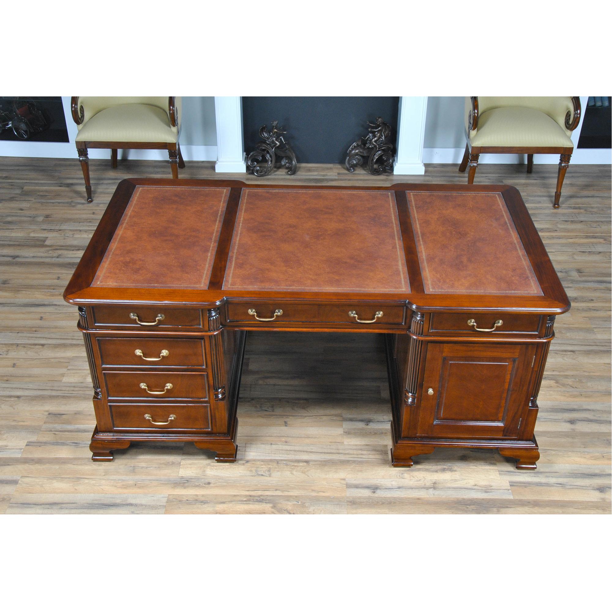 A fine quality Mahogany Partners Desk from Niagara Furniture with raised door panels and a rich brown color finish similar to that found in English antiques. The three-paneled writing surface of brown, full grain genuine leather features antique