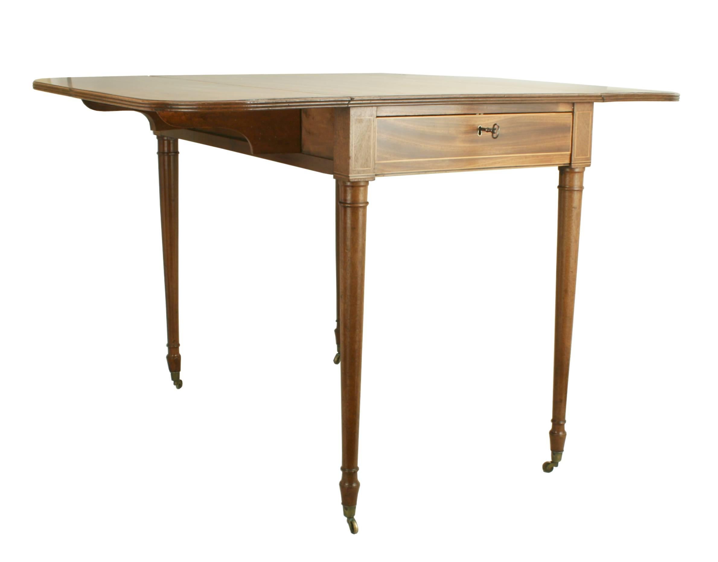 Mahogany Pembroke table.
A very nicely inlaid drop-leaf Pembroke table. The table has a rounded rectangular drop-leaf top with satinwood crossbanding with further ebony and boxwood stringing. There is a single drawer with an opposing dummy drawer