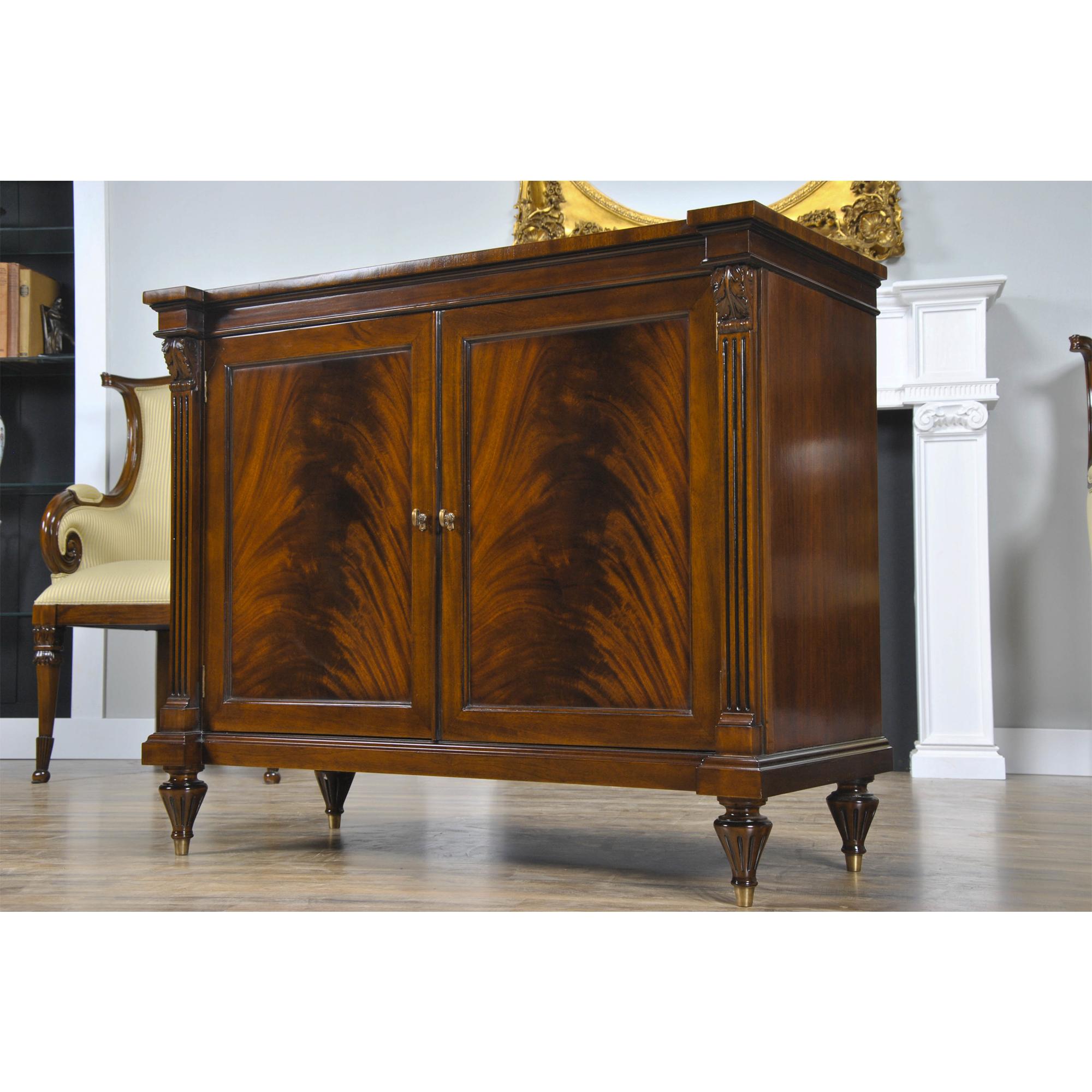A fine quality Mahogany Penhurst Server Cabinet with two large figural paneled doors opening to reveal a single wooden shelf. Block front reeded columns surround the doors and feature hand carved solid mahogany decorations on top. The entire
