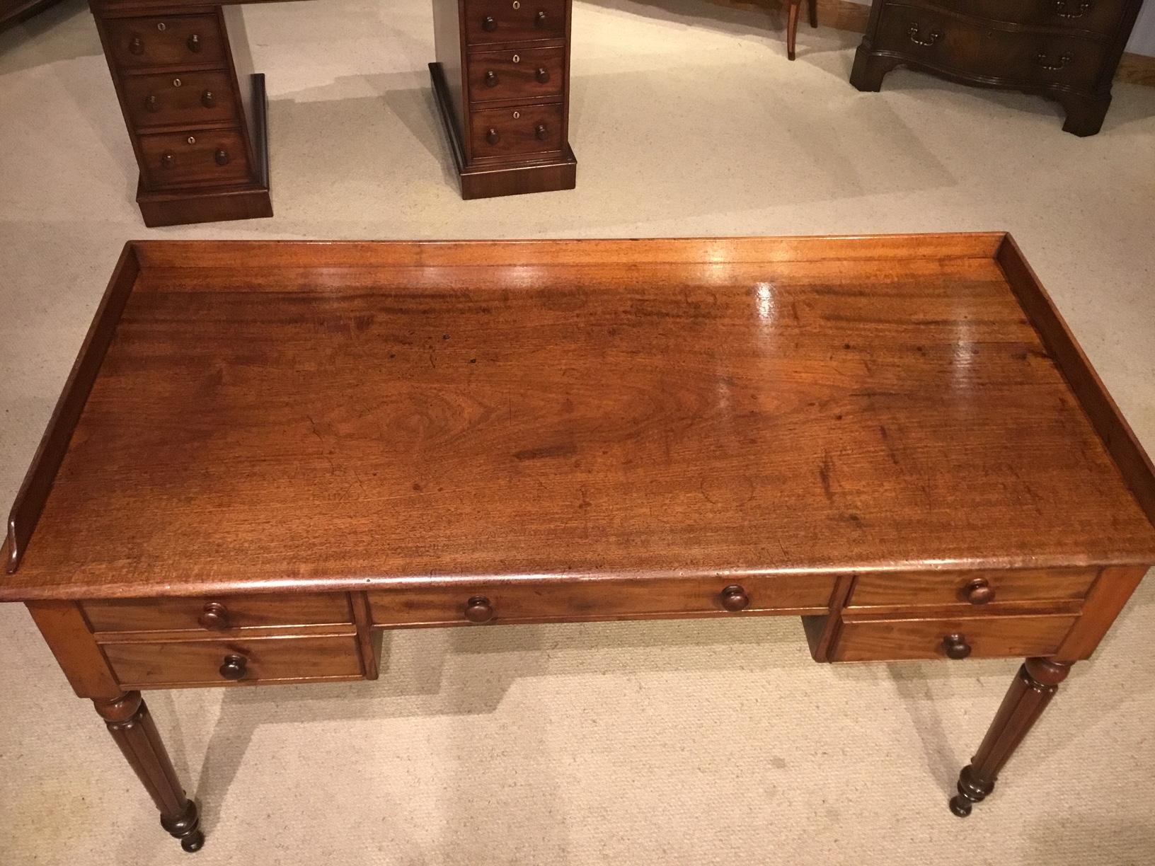 A mahogany Regency period dressing table or side table. Having a superb one piece Cuban mahogany top with a raised galleried back above an arrangement of five rectangular mahogany lined drawers, retaining their original mahogany turned knobs.