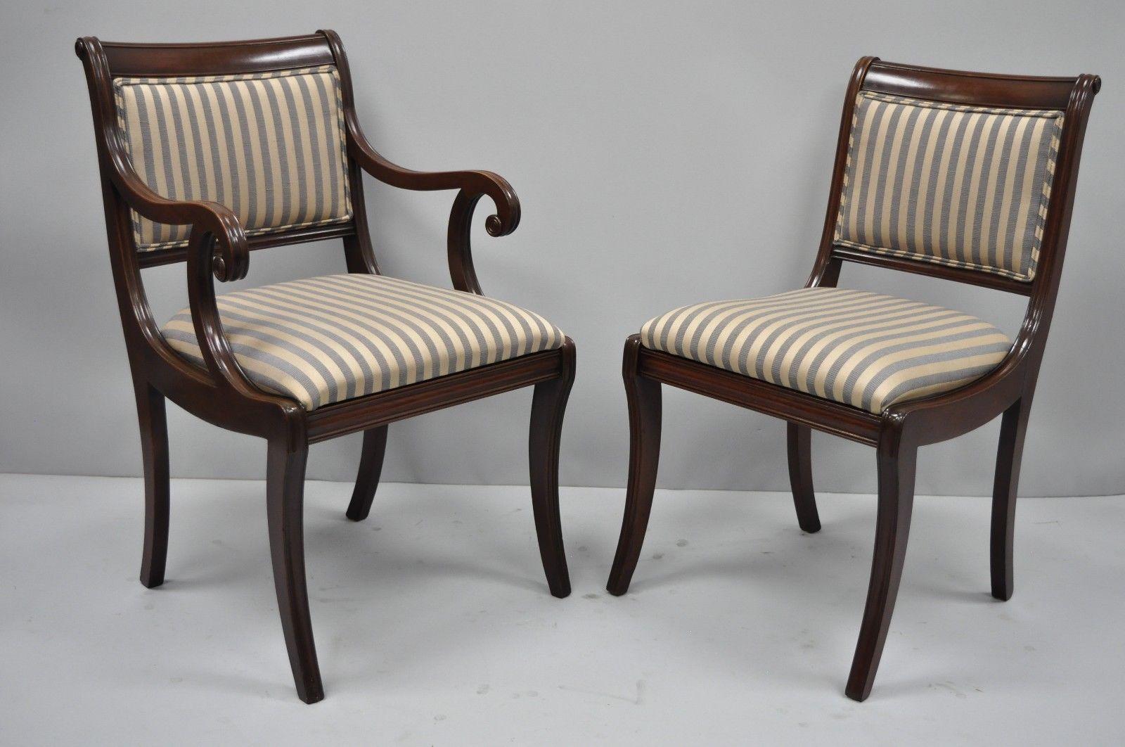 Set of six antique mahogany saber leg Regency style dining chairs. Item features four side chairs, two arm chairs, newer blue and tan or gold striped fabric, solid wood construction, shapely saber legs, and quality American craftsmanship, circa