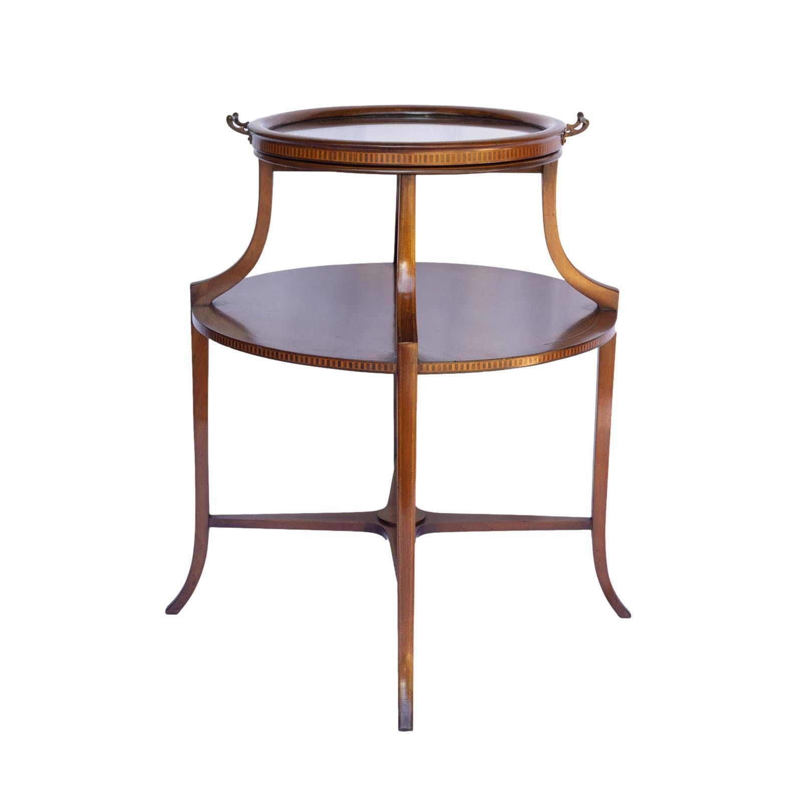Mahogany round two-tier serving table, with satinwood inlays and stringing, with a shaped stretcher, on sabre legs with further fine checkered inlays, the removable tray with solid brass mounted handles. 
In exceptional antique condition, and