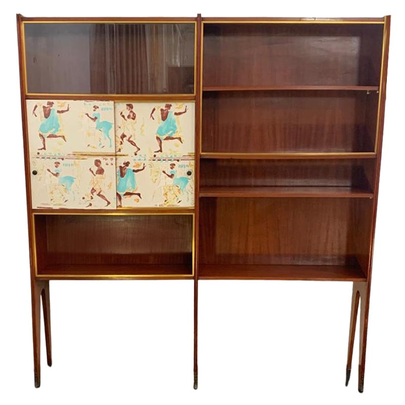 Libreria Showcase (1 di 2) in mogano biondo, anni '50
Caratterizzato da piedini in bronzo e finiture in ottone, questo mobile presenta due ante con decorazioni ispirate al classicismo greco.
Lo stile, il design e i pannelli decorativi ricordano