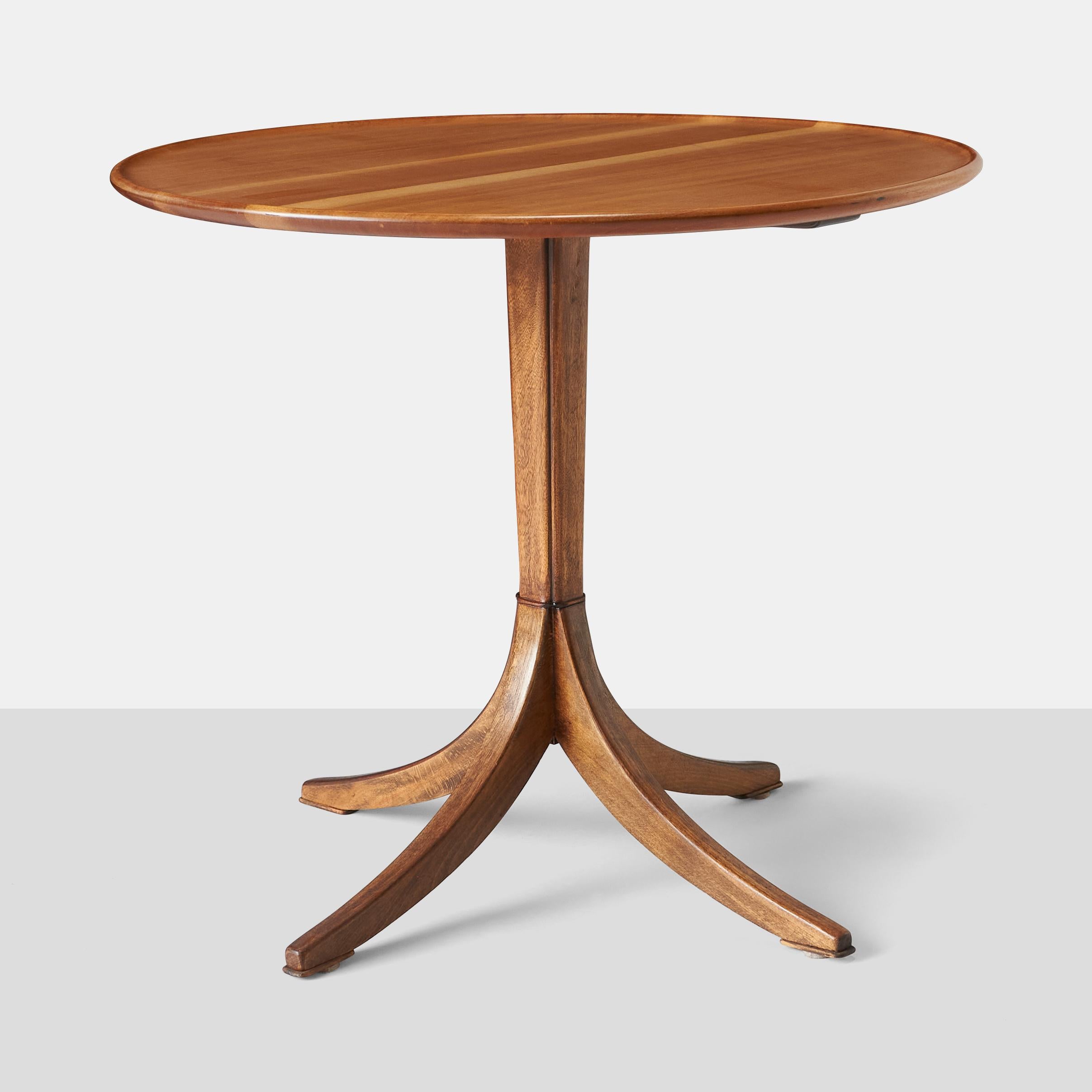 Circular table with rimmed and raised panel made of solid mahogany, with center column and four-star base.