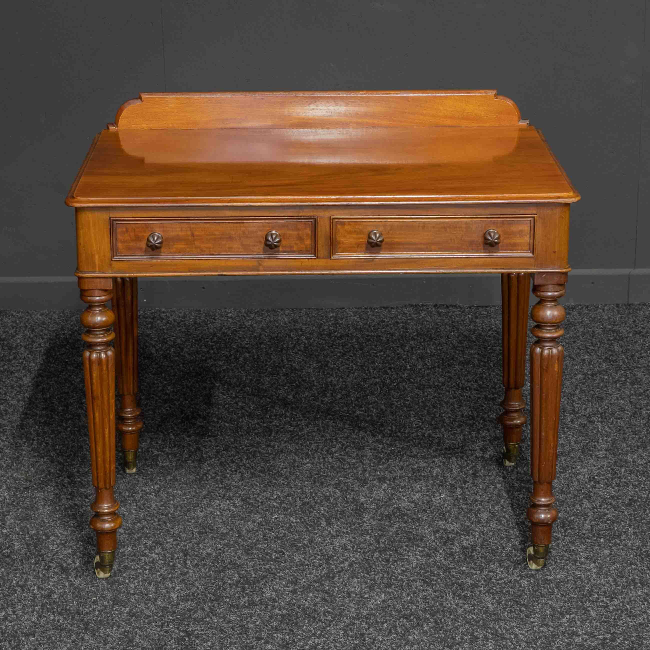 A superb late Regency/ William IV mahogany side table stamped to the top of the left hand drawer 'Maple - London'. With typical turned and fluted legs which still retain their original castors. A pair of drawers with superb knobs that also have