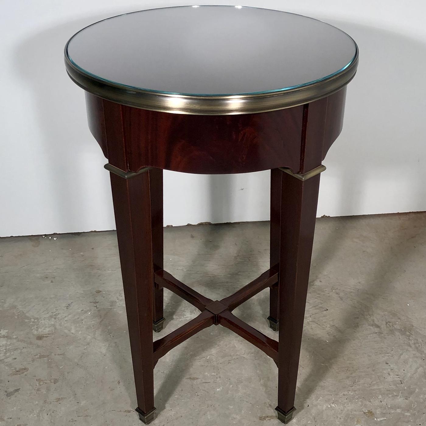 This stunning side table brings style and flair to any traditional living room, boasting tapered legs and a decorative cross base. Beautifully crafted from solid mahogany with a rich brown tone, this round table is enhanced with brass accents with a