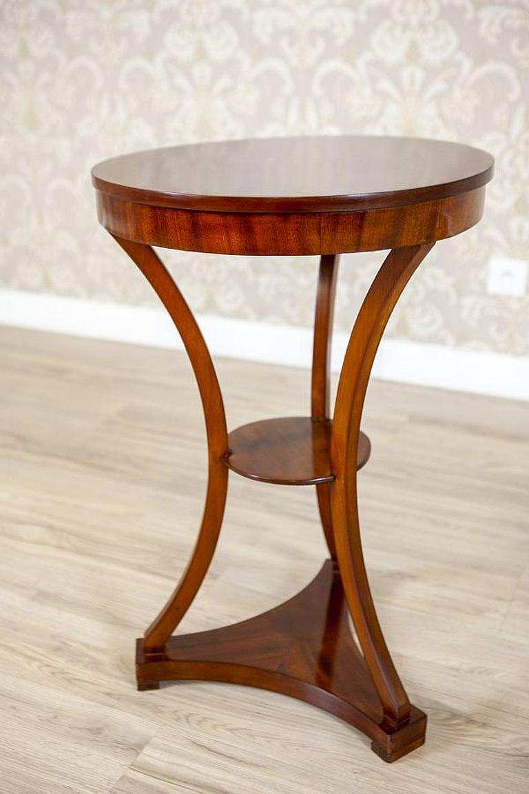Mahogany side table from the early 20th century.

We present you this neat mahogany side table. Its round table is made of a single piece of wood. The whole is placed on three bent legs, which are placed on a base. At half of its height, the table