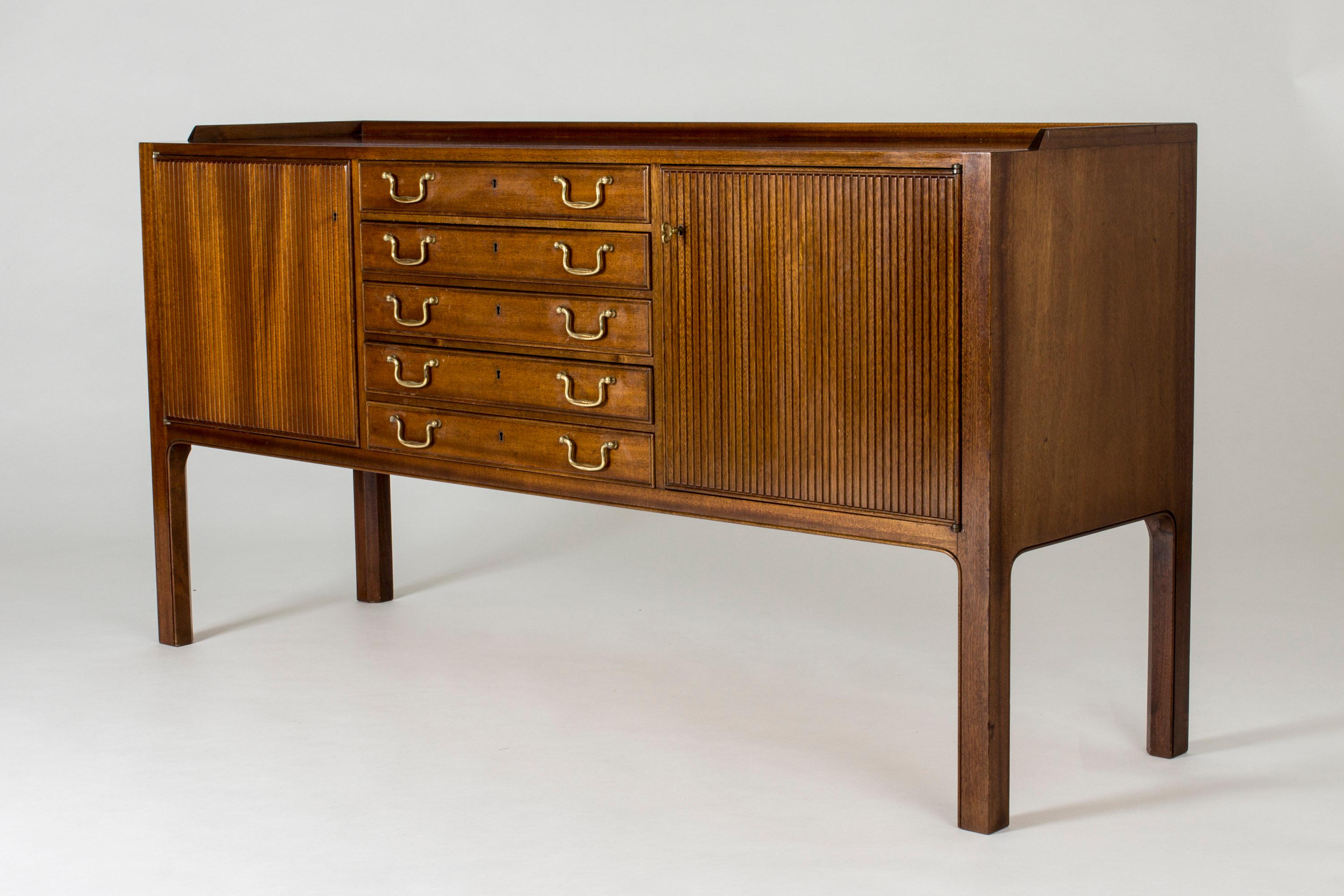 Elegant mahogany sideboard by David Rosén, with embellished stripes fronts and drawers with brass handles. Very nice attention to detail, like in the curved angle where the legs come down from the body.
