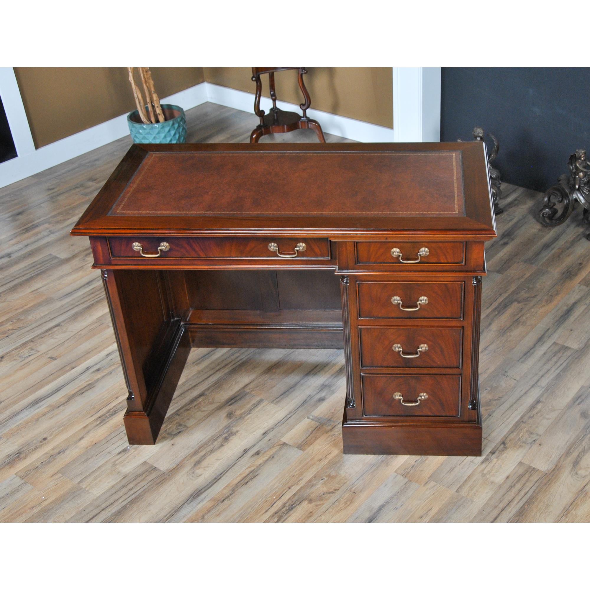 A fine quality Mahogany Single Bank Desk from Niagara Furniture with raised side panels and a rich brown color finish similar to that found in English antiques. The writing surface of brown, full grain genuine leather features antique style gold