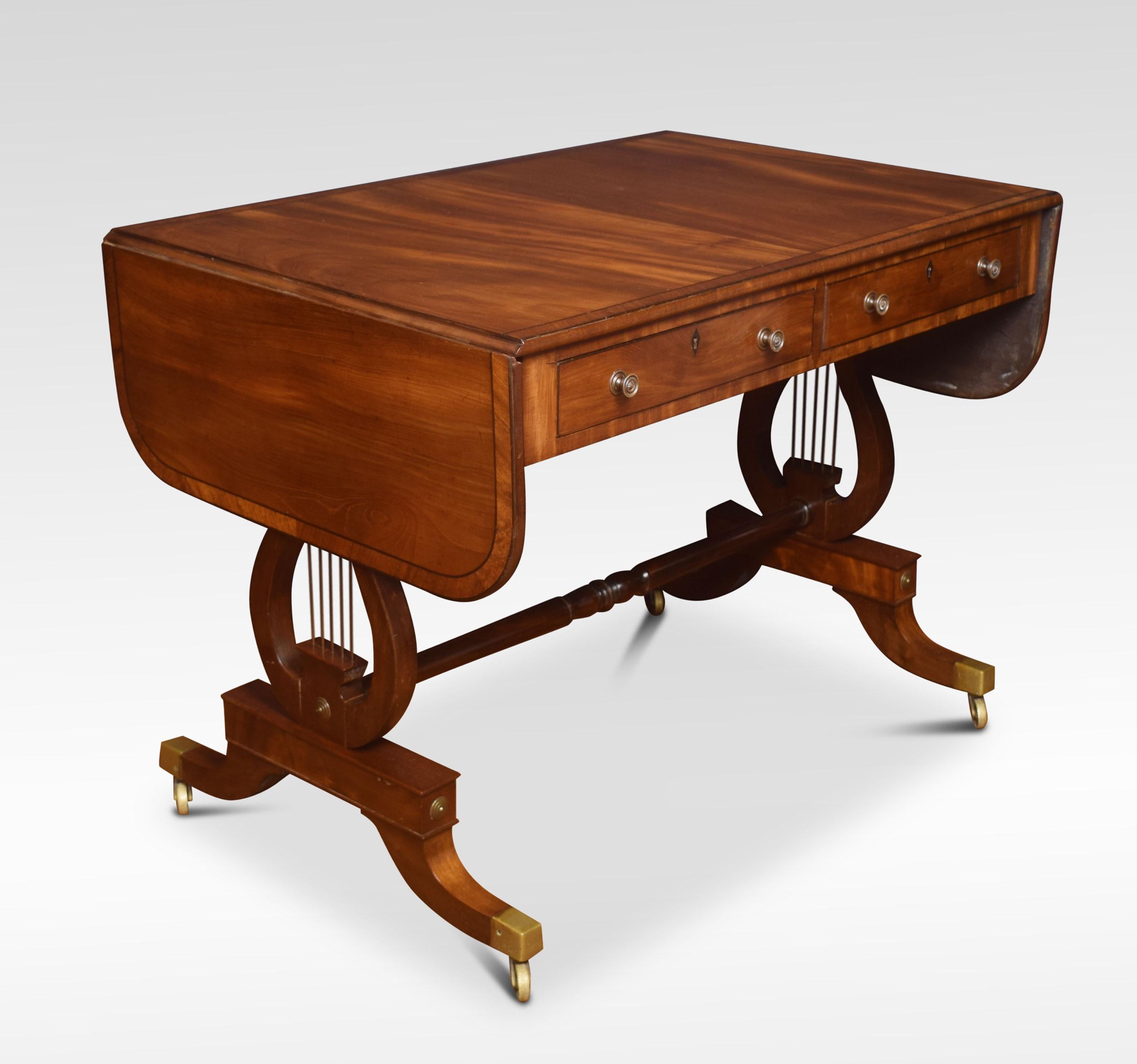 Late 19th century mahogany sofa table, the rectangular top with rounded corners, and two drop leaves having crossbanded detail. Above two freeze drawers the opposing side having faux drawers. All raised up on a pair of lyre ends united by stretcher
