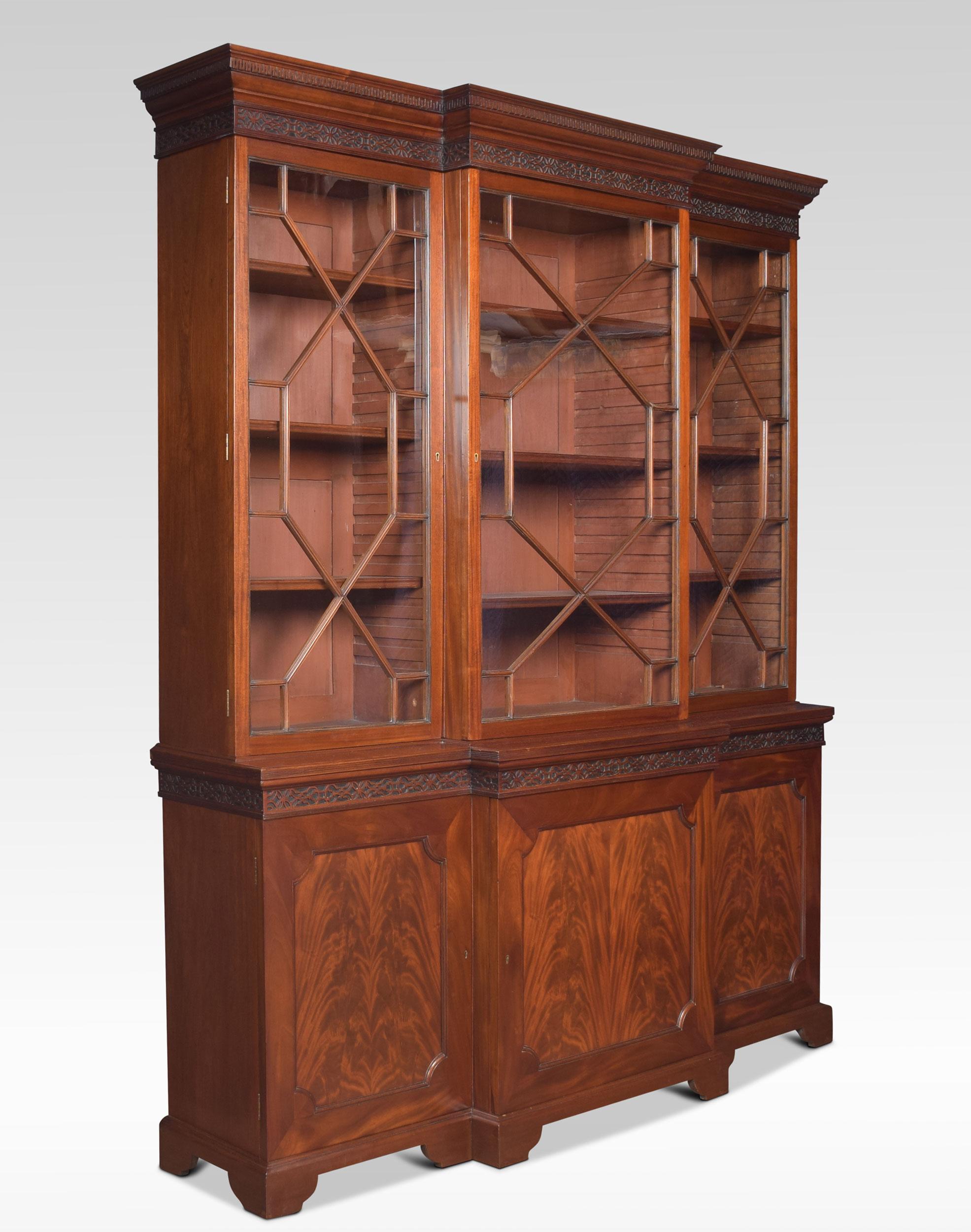 Large Chippendale revival mahogany bookcase the carved moulded blind fret projecting cornice, above one large central astragal glazed door flanked by two further small glazed doors opening to reveal an adjustable shelved interior. To the base
