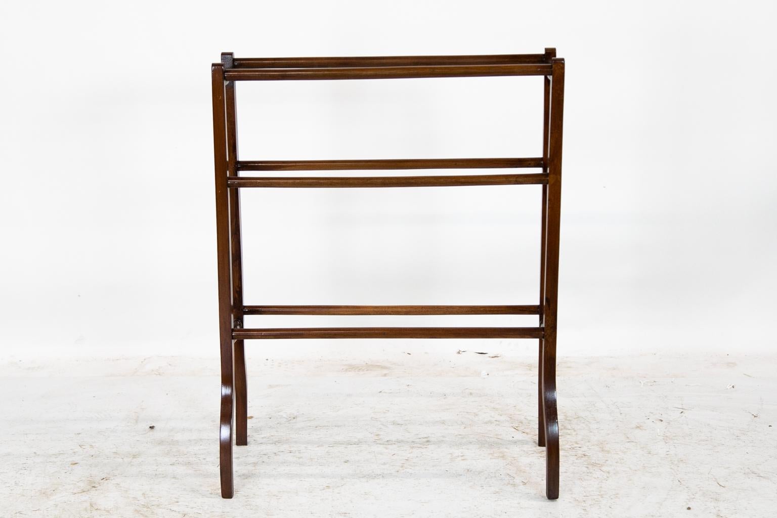 This mahogany towel/blanket rack has six hanging bars. The legs are connected by turned cross supports that terminate in legs that splay out at the foot for added stability.
