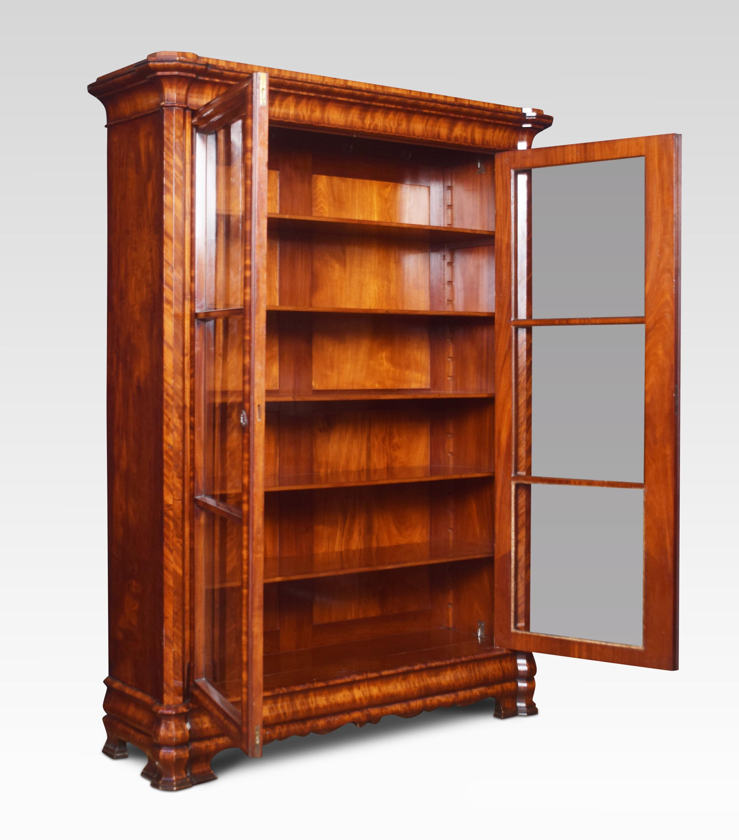 Mahogany bookcase, the moulded cornice above two glazed doors enclosing five adjustable shelves and polished flame mahogany back. To the stepped base, all raised up on bracket feet.
Dimensions:
Height 75.5 inches
Width 57 inches
Depth 18 inches.