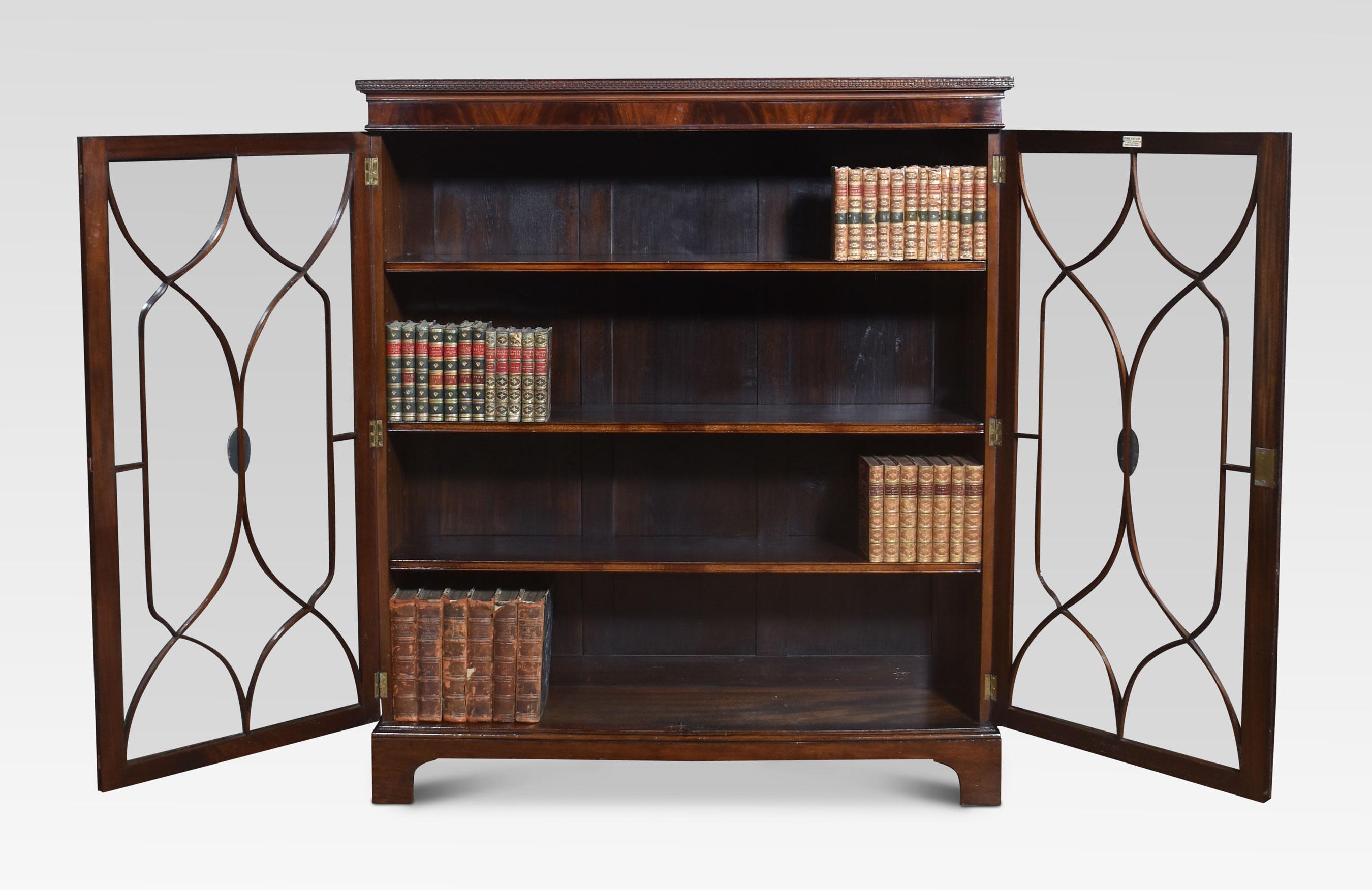 Mahogany two-door glazed bookcase, the rectangular well-figured top having carved moulded edge. Above two large astragal glazed doors opening to reveal three adjustable shelves. All raised on bracket feet

Dimensions
Height 55 Inches
Width 48
