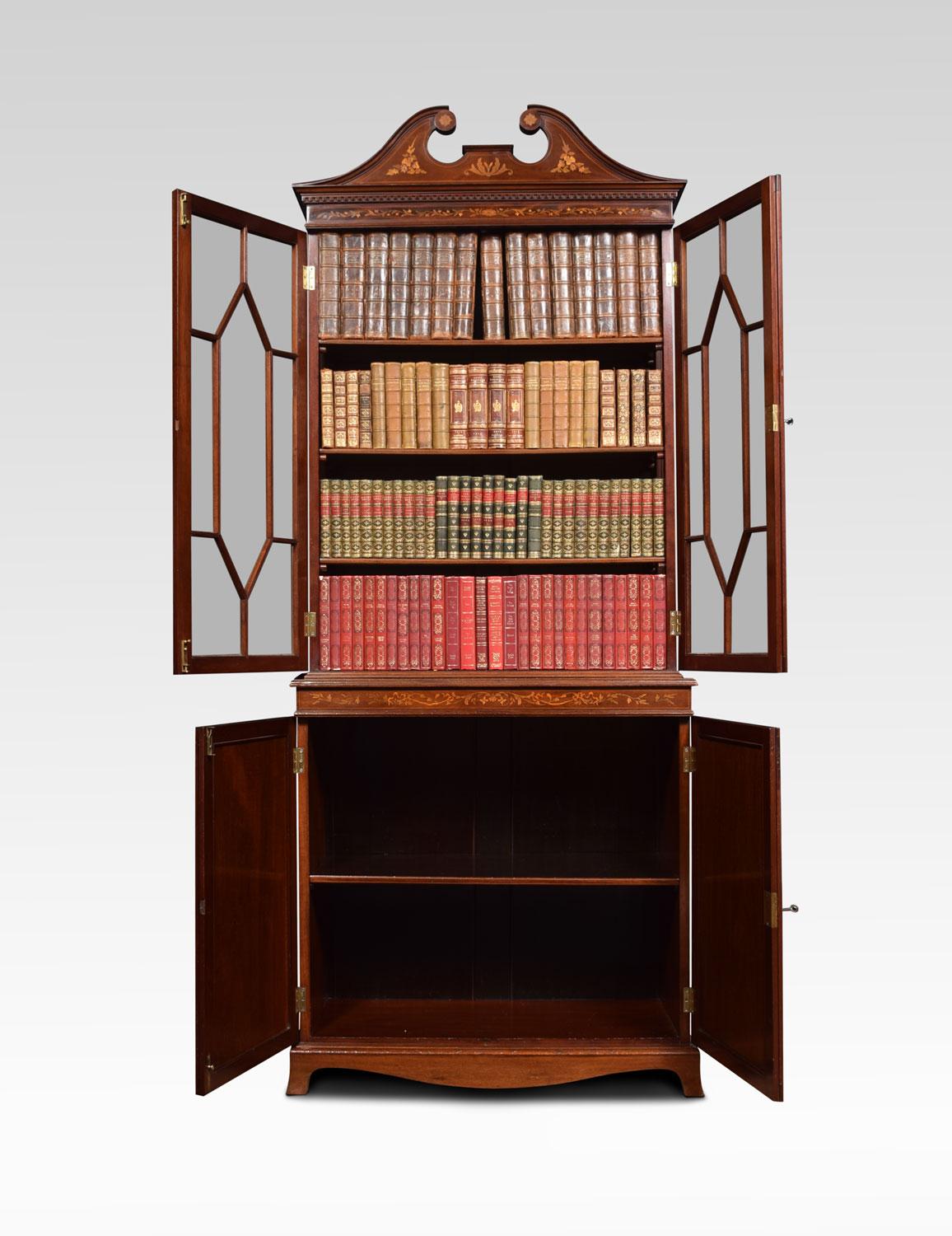 Mahogany inlaid cabinet or bookcase in the manner of Edwards & Roberts of London. The upper section with swan neck pediment and marquetry pen-work frieze. The twin astragal glazed doors open to reveal shelved interior. The solid mahogany sides with