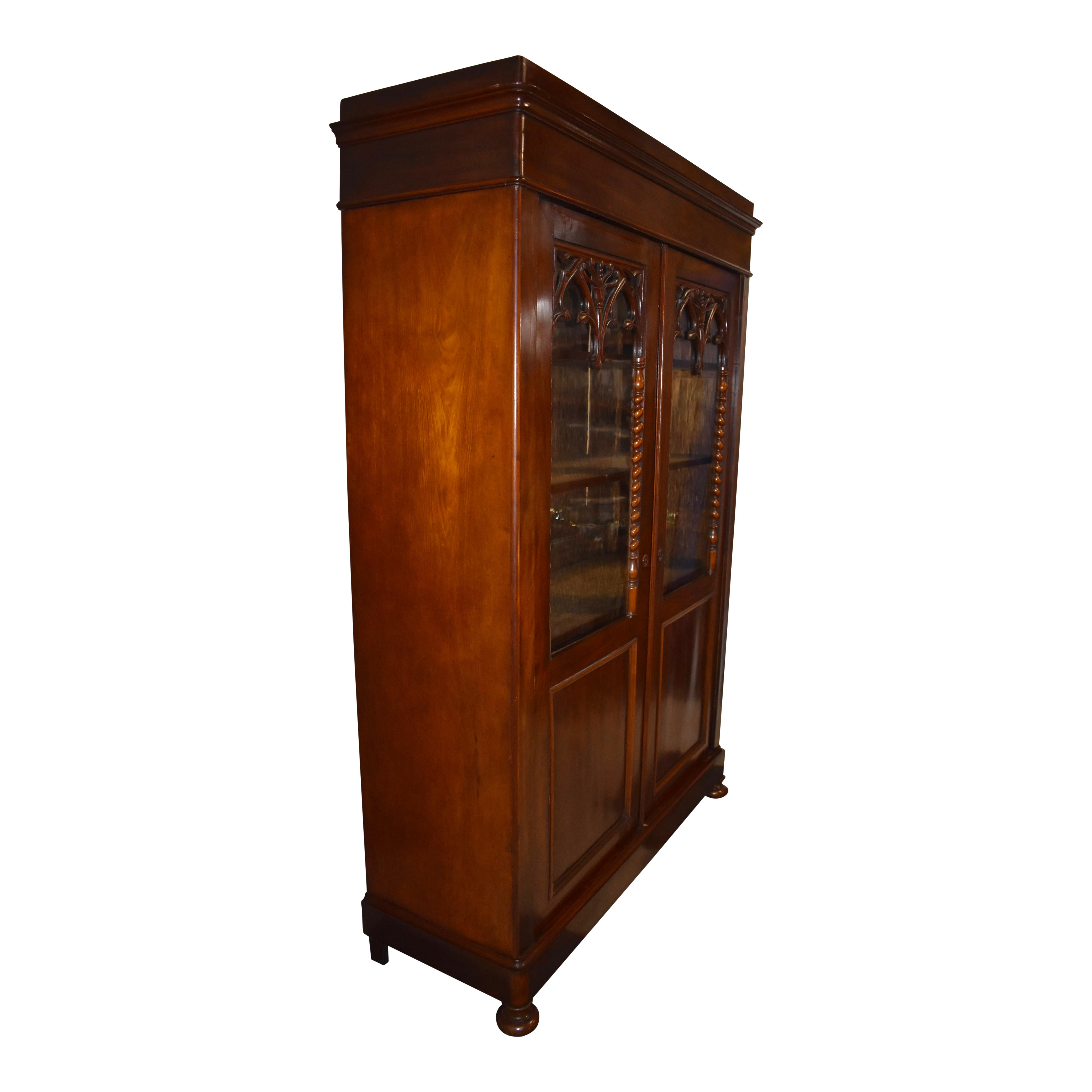 Crafted from mahogany veneer and solid oak that have been finished in a rich, dark stain consistent with mahogany's reddish-brown tones, this antique vitrine from the turn of the 20th century features two doors with glass panes for showcasing your