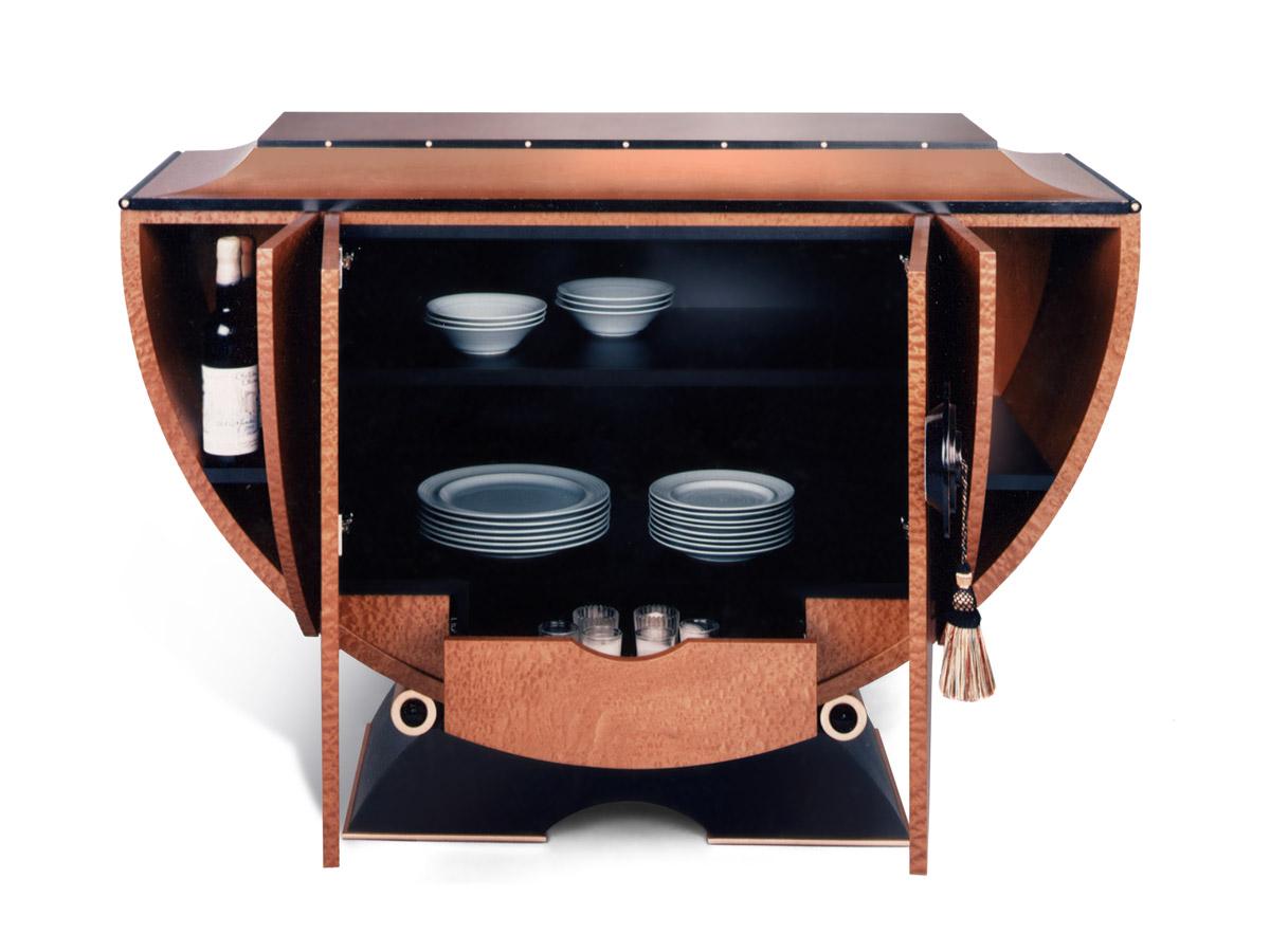 The Tympany buffet is a figured wood cabinet exterior with jet black and metal leaf detailing. The handles are accented by a multi-colored silk tassel which complements the natural mahogany interior. All the shelves inside the cabinet are adjustable