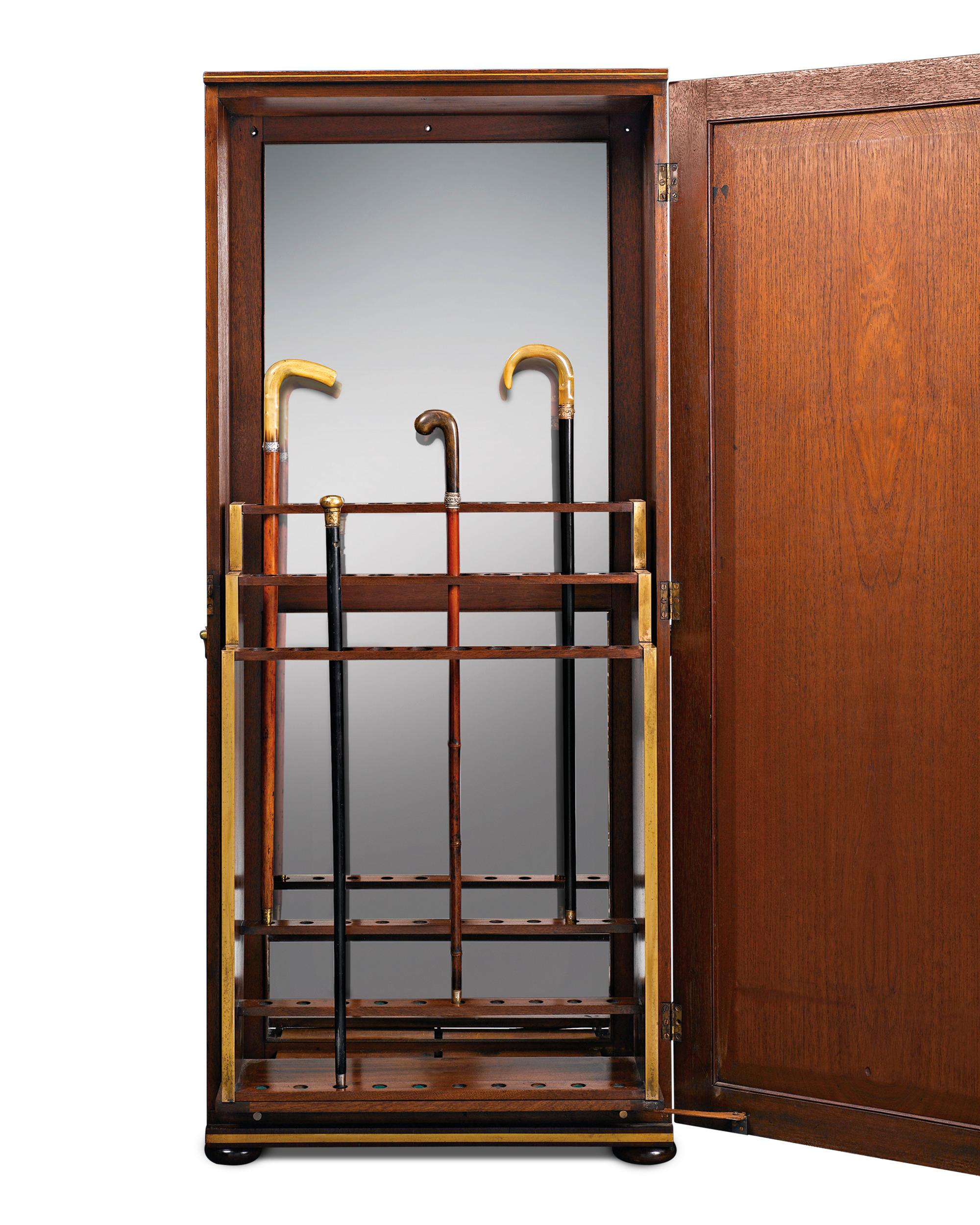 Classical style and impeccable design distinguish this English upright cane cabinet. Crafted of lustrous Cuban mahogany, this case is comprised of a beautifully paneled door which opens to reveal a three-tiered cane rack that holds 30 walking