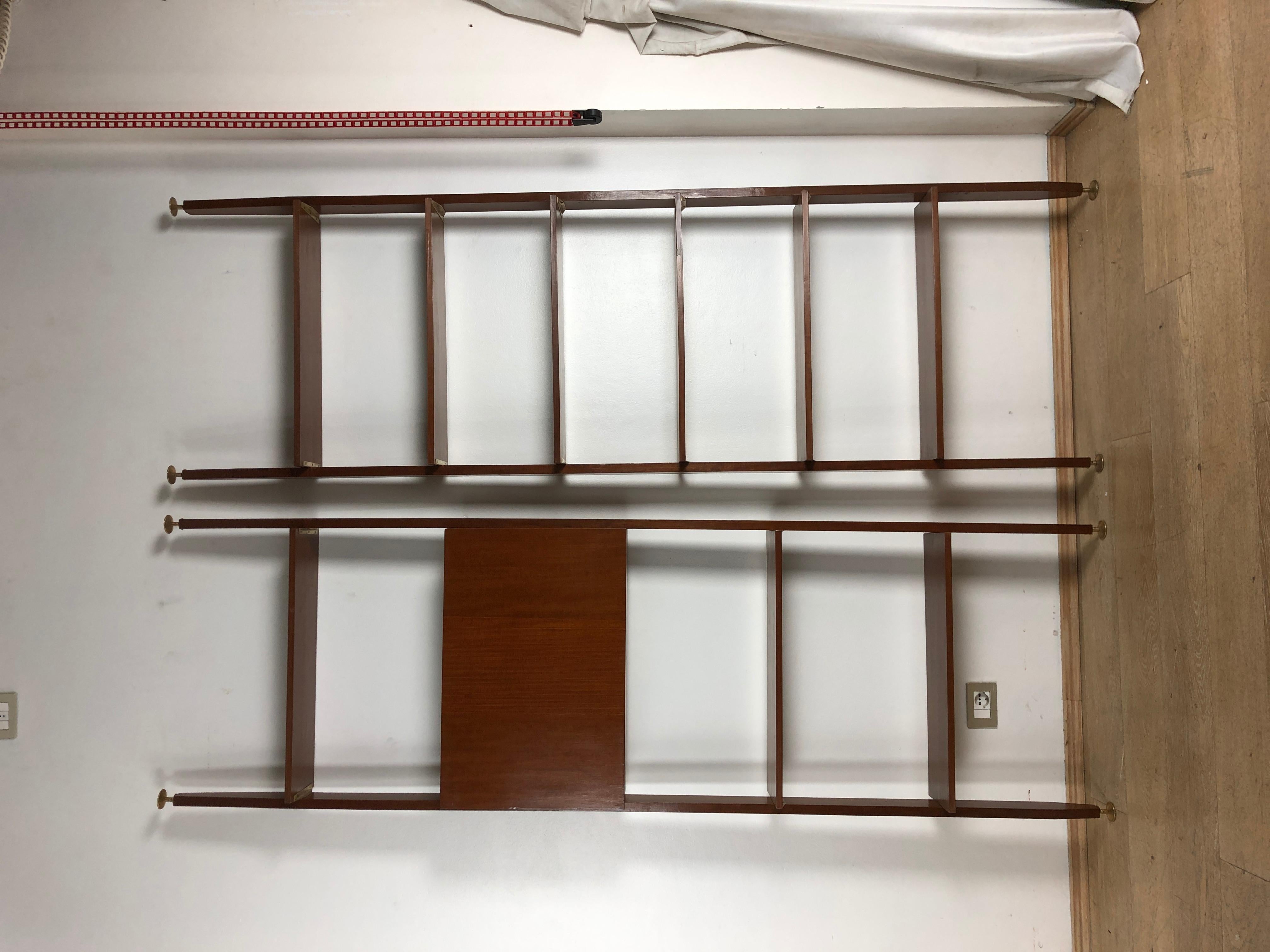 Modular mahogany pair of bookcases consisting of vertical supports, a storage unit with swing door, and adjustable shelves. 
The structure can be fixed both to the ceiling and to the wall with brackets. Each bookcase module measures H 240 cm W 73