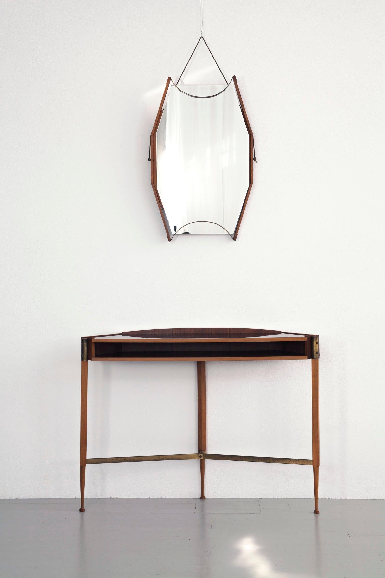 This mahogany wall console with black formica top and a wall mirror was manufactured in 1950 in Italy. Its extraordinary design is built from a combination of fine, straight shapes and rustic, angular elements like the concise brass fittings.

Feel