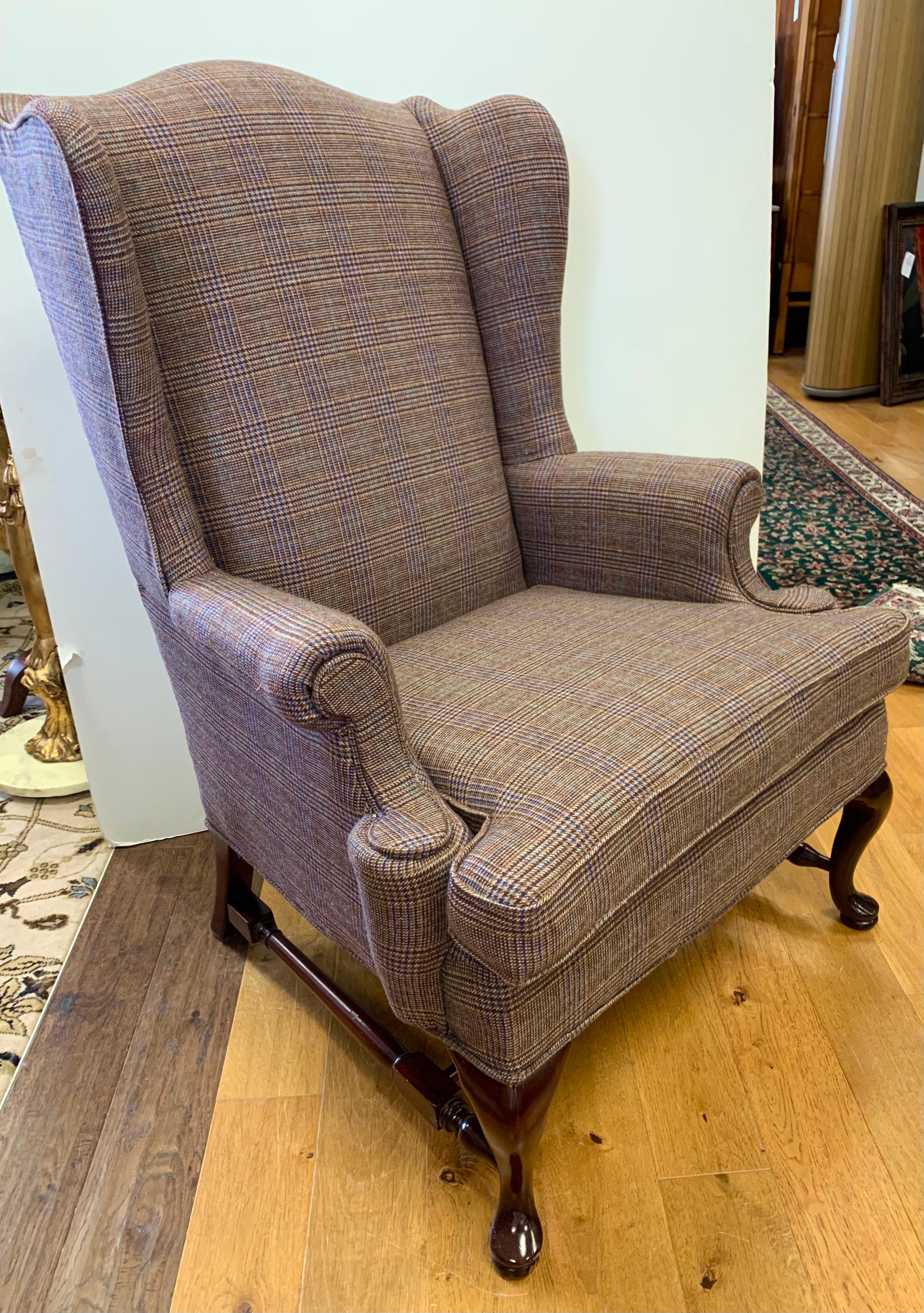 Handsome Classic wingback chair with mahogany legs and cross stretcher has been newly reupholstered in a luxurious Ralph Lauren tartan wool plaid fabric. The tartan plaid fabric melds perfectly with the dark, rich mahogany feet. Arms have removable