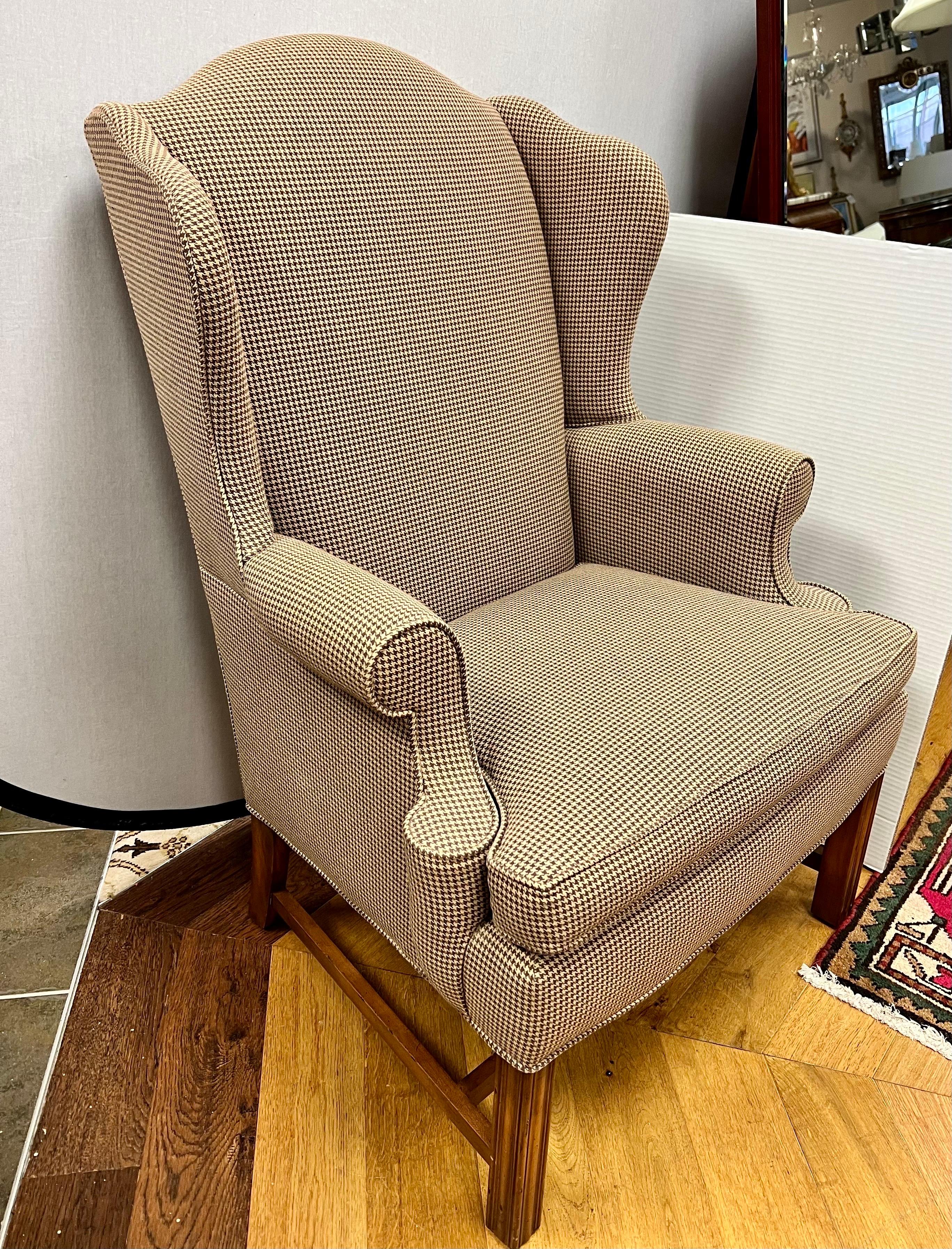 Classic wingback upholstered reading chair with brown and beige houndstooth fabric and mahogany frame.