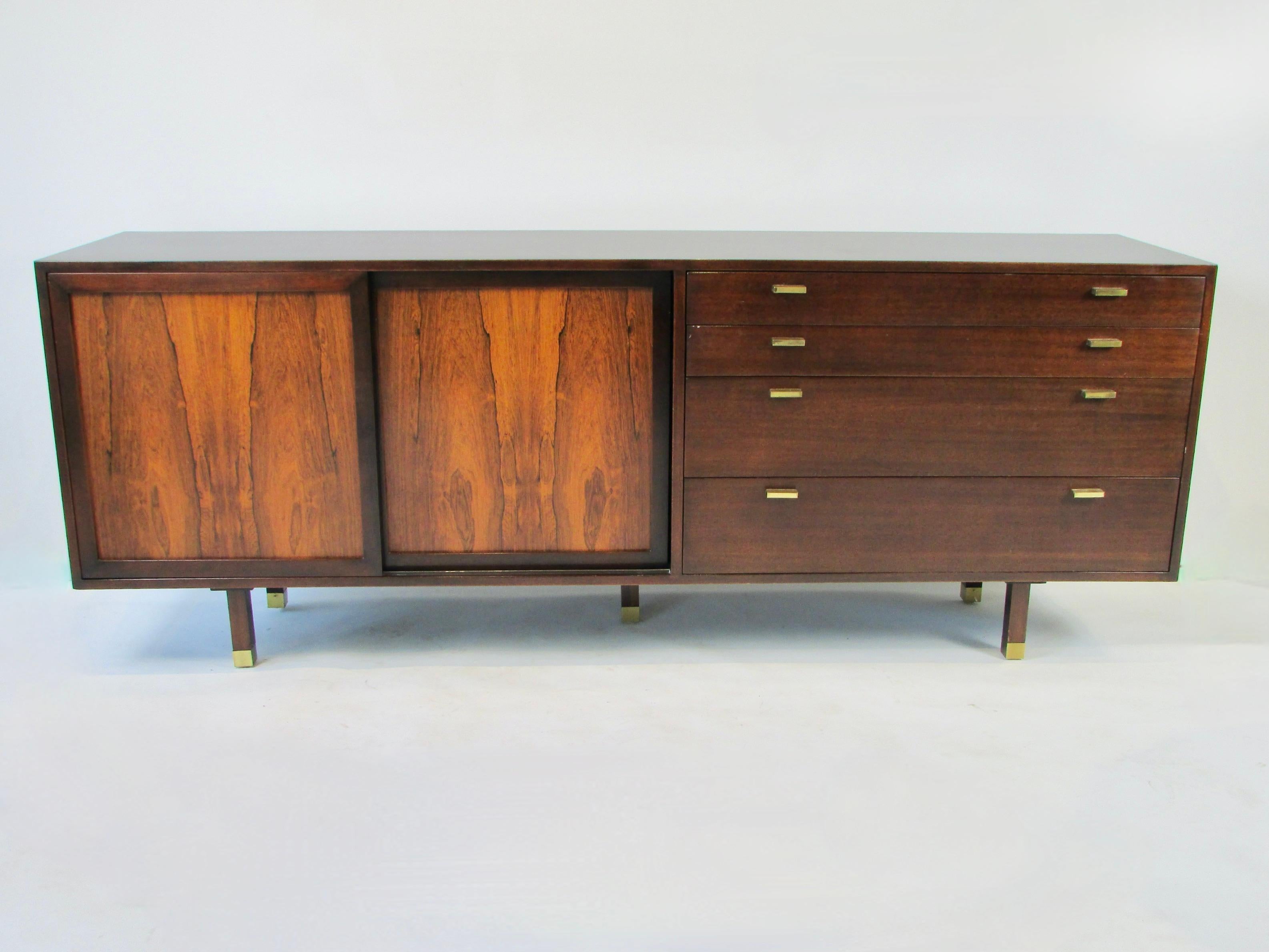 Large 6 foot five inch long mahogany cabinet housing two rosewood sliding doors alongside four graduated drawers. One door holds adjustable shelves second door slides open to reveal pair of cork lined drawers. Drawers of the credenza open with solid