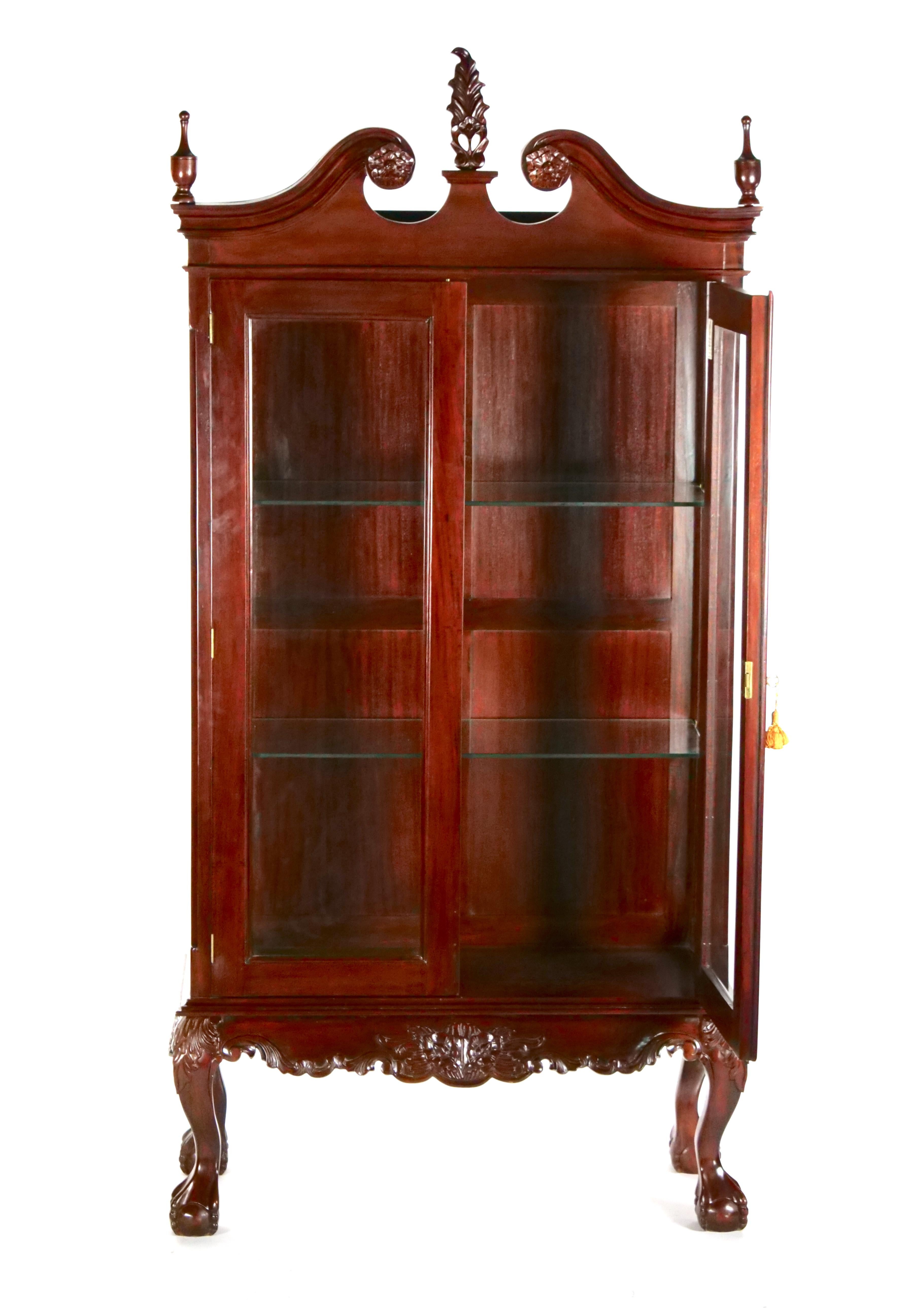 Early 20th century mahogany wood frame and glass display cabinet with two adjustable glass shelves. The cabinet features two front glass door with two interior removable glass shelve resting on four ball claw feet and three top finials. The cabinet