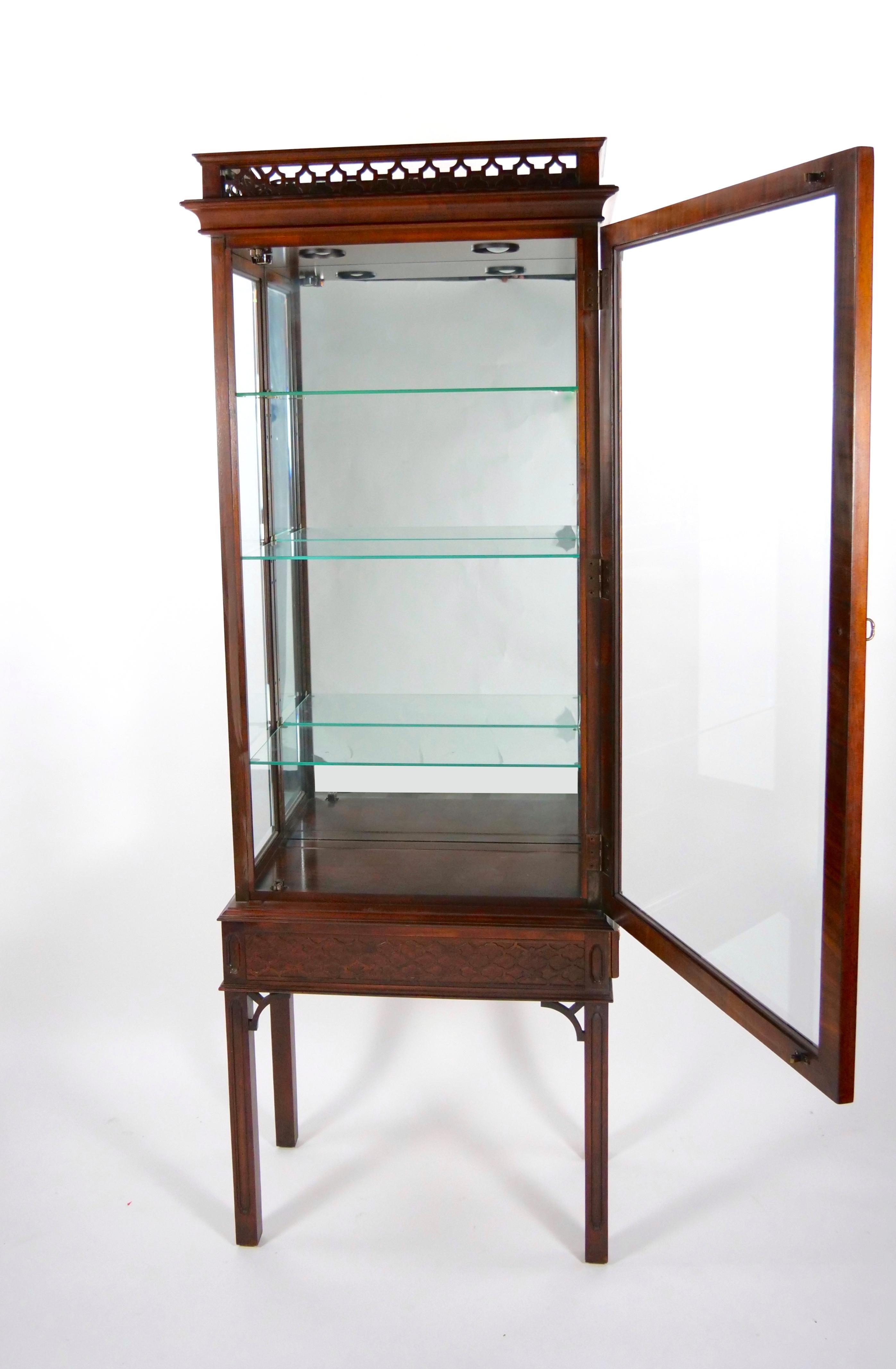 Elevate your living space with this Early 20th Century North American Mahogany Wood Framed Mirrored Vitrine, a piece of furniture that exudes elegance and timeless charm. The mirrored backsplash creates a sense of depth and luminosity, enhancing the