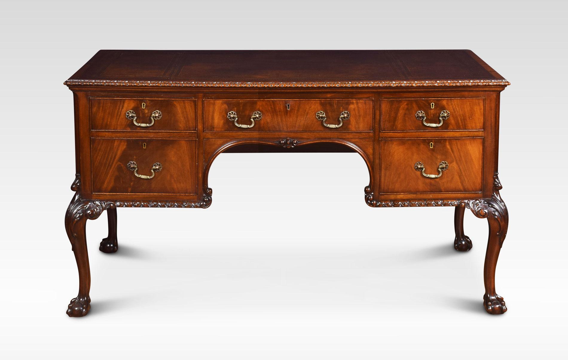 Mahogany writing desk, of Chippendale design, the inset tooled leather writing surface, within an egg and dart border. Above central frieze drawer flanked by two further drawers to each side. All raised up on cabriole legs with claw and ball