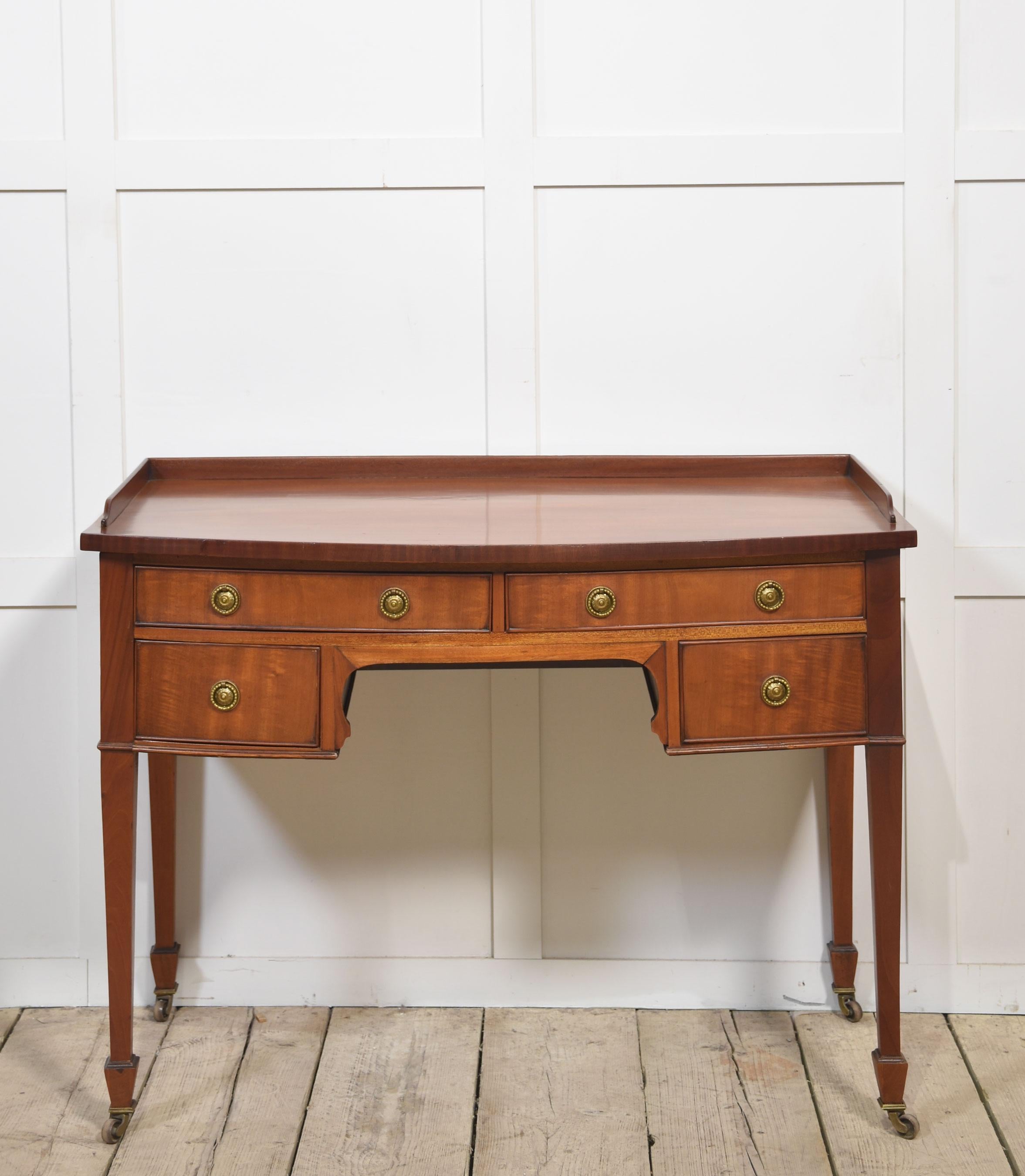 Table à écrire en acajou, le plateau rectangulaire à galerie trois-quarts en relief. Au-dessus, un arrangement de tiroirs avec des poignées en laiton. Le tout repose sur quatre supports effilés terminés par des roulettes en