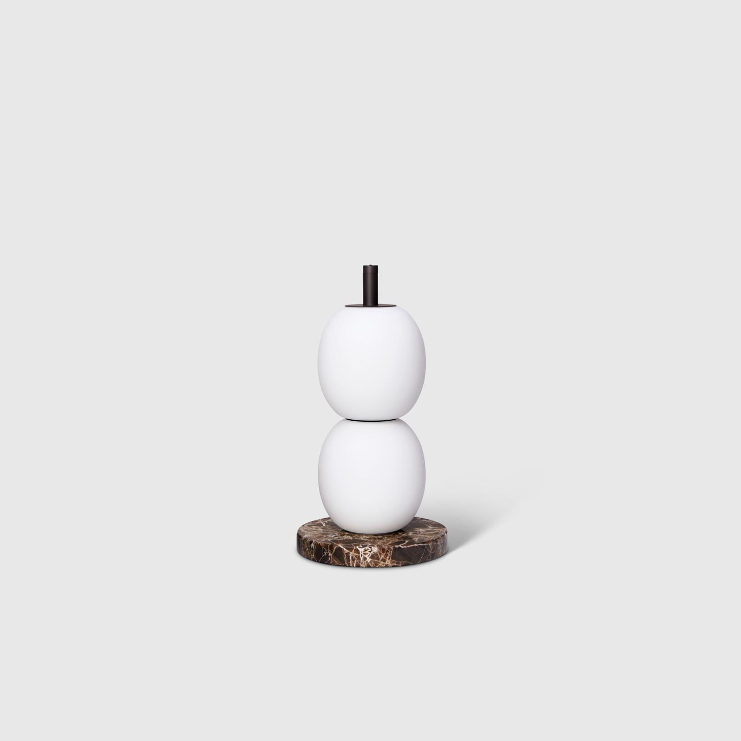 The Mainkai table lamp by Sebastian Herkner matches his playful shapes with sophisticated materials. The lamp’s integrated button on the top stem dims the glow of its hand blown glass globes. The LED light has a balanced color temperature of 2700K
