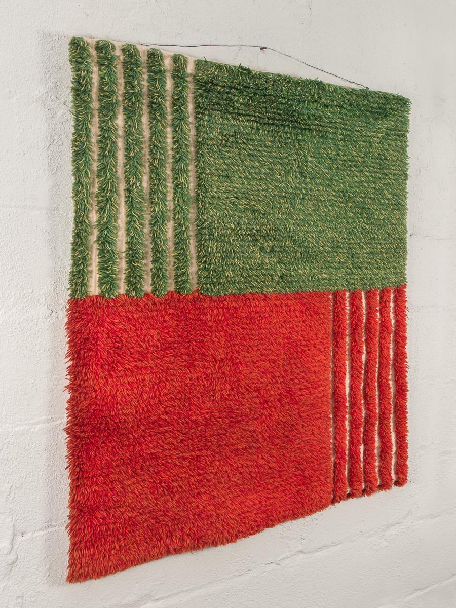 Long-tufted hanging Ryijy textile crafted by Finnish artisan Maisa Kaarna. A 19th century craft, the knotted-pile technique has since been passed along as revered Folk Art unique to Finland. This modern example is a brilliant green and red, two-tone